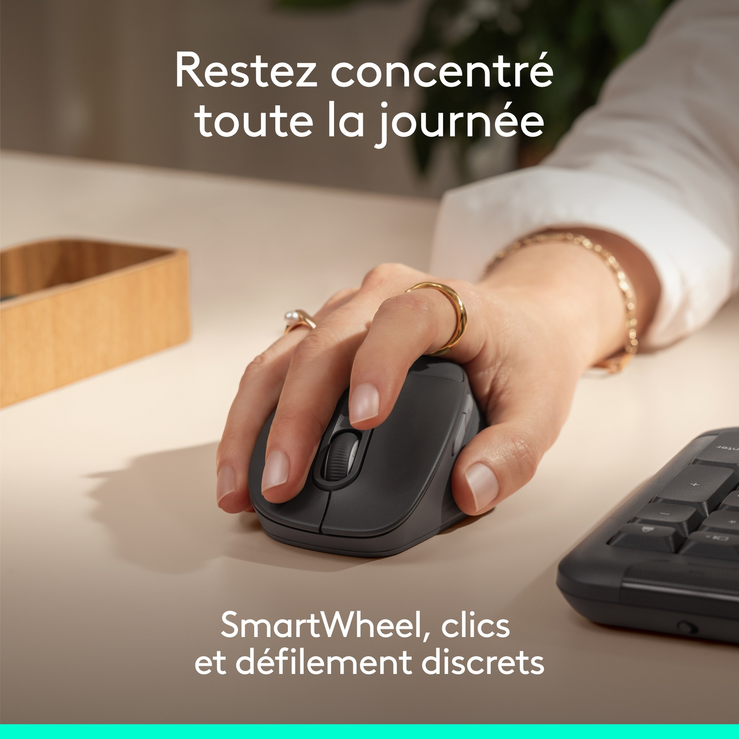 Une main utilise une souris grise sur un bureau. Du texte est superposé.