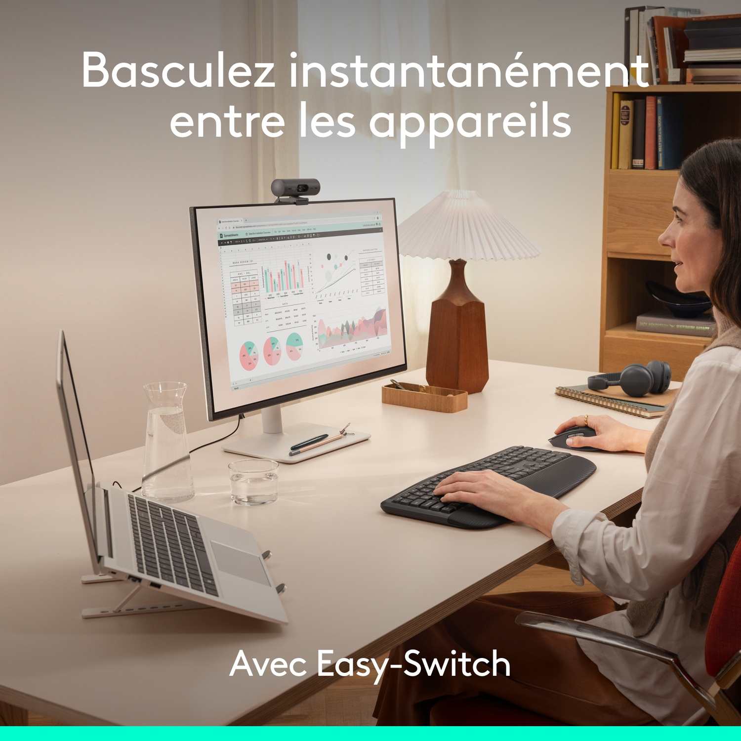 Femme travaille à un bureau avec ordinateur portable, écran, clavier et souris.
