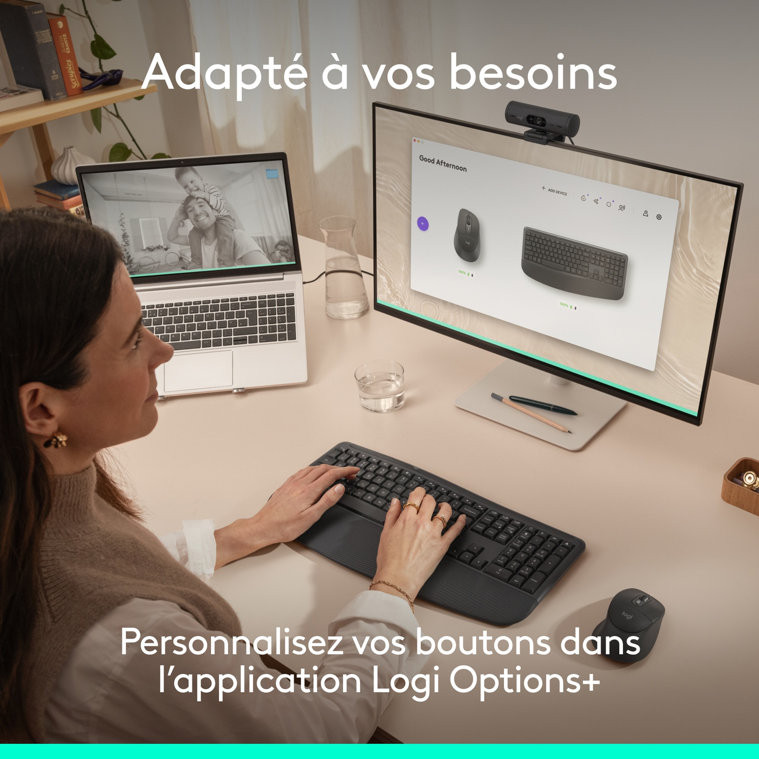 Une femme tape sur un clavier, un ordinateur portable et un moniteur sont visibles.