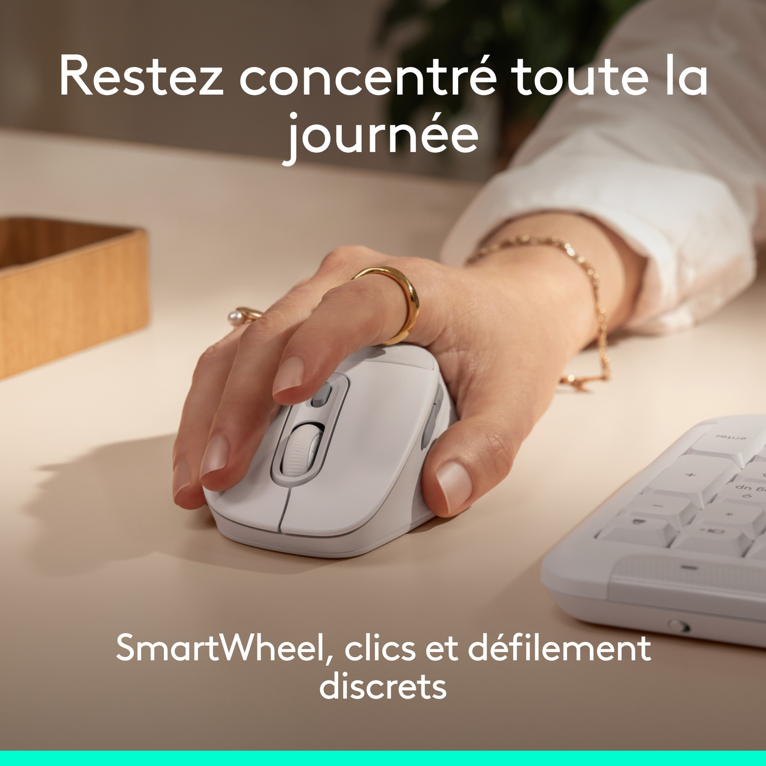 Une souris blanche est manipulée par une main, à côté un clavier.