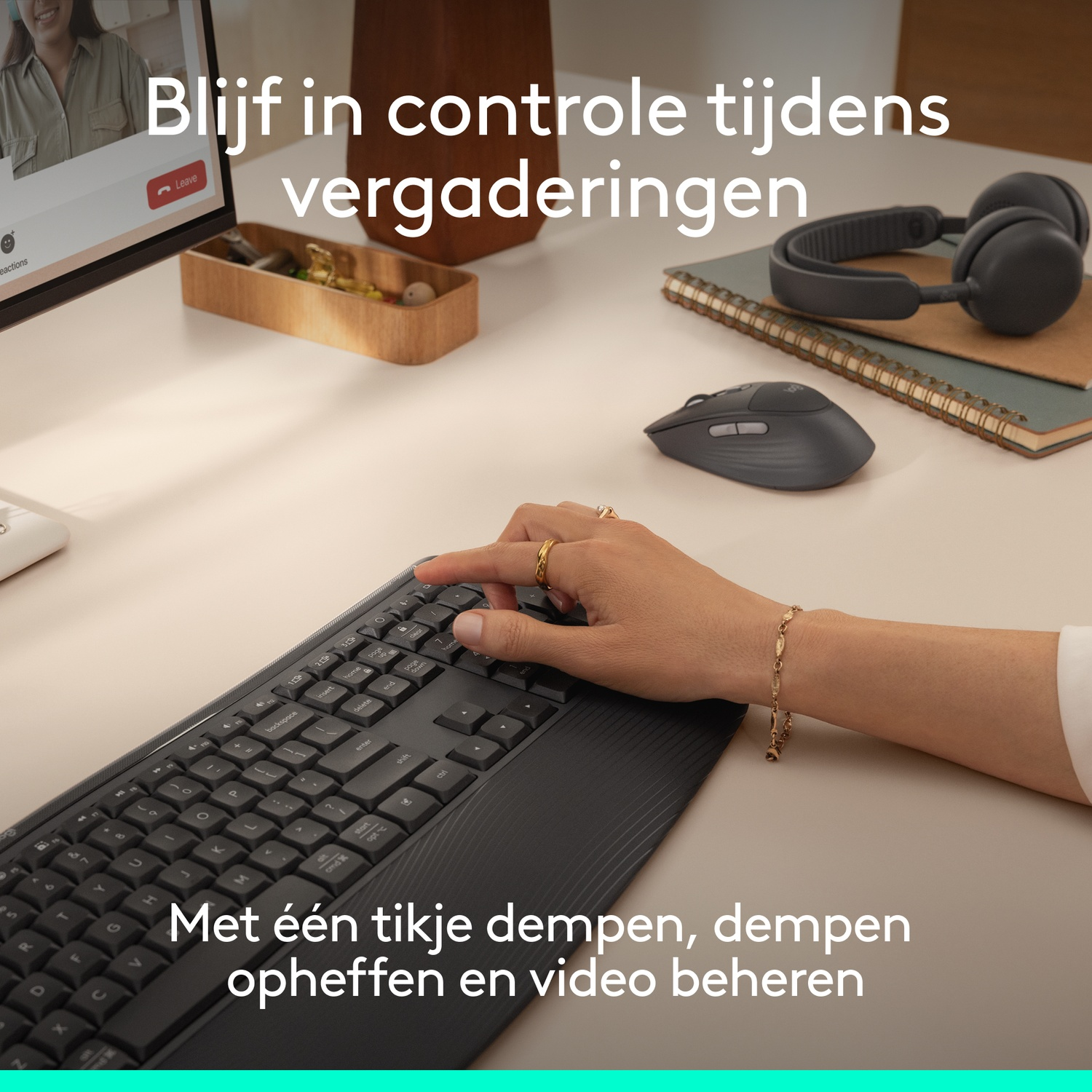 Person's hand on a keyboard, computer screen, mouse, and headphones on a desk.
