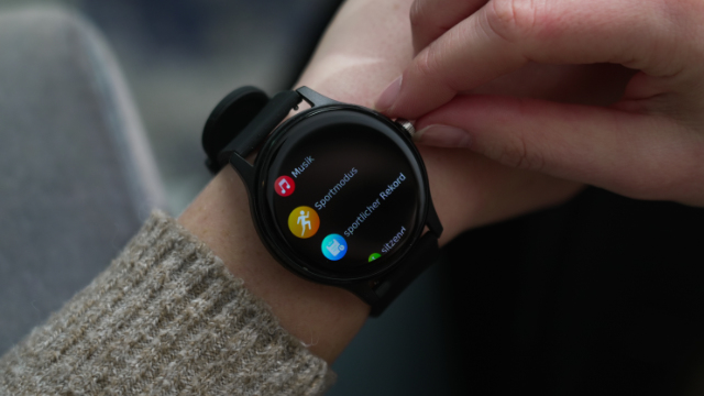 Eine Person bedient eine Smartwatch mit Sport- und Musik-Apps auf dem Display.