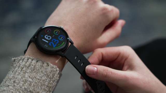 Eine Person trägt eine Smartwatch mit bunten Zifferblättern am Handgelenk.