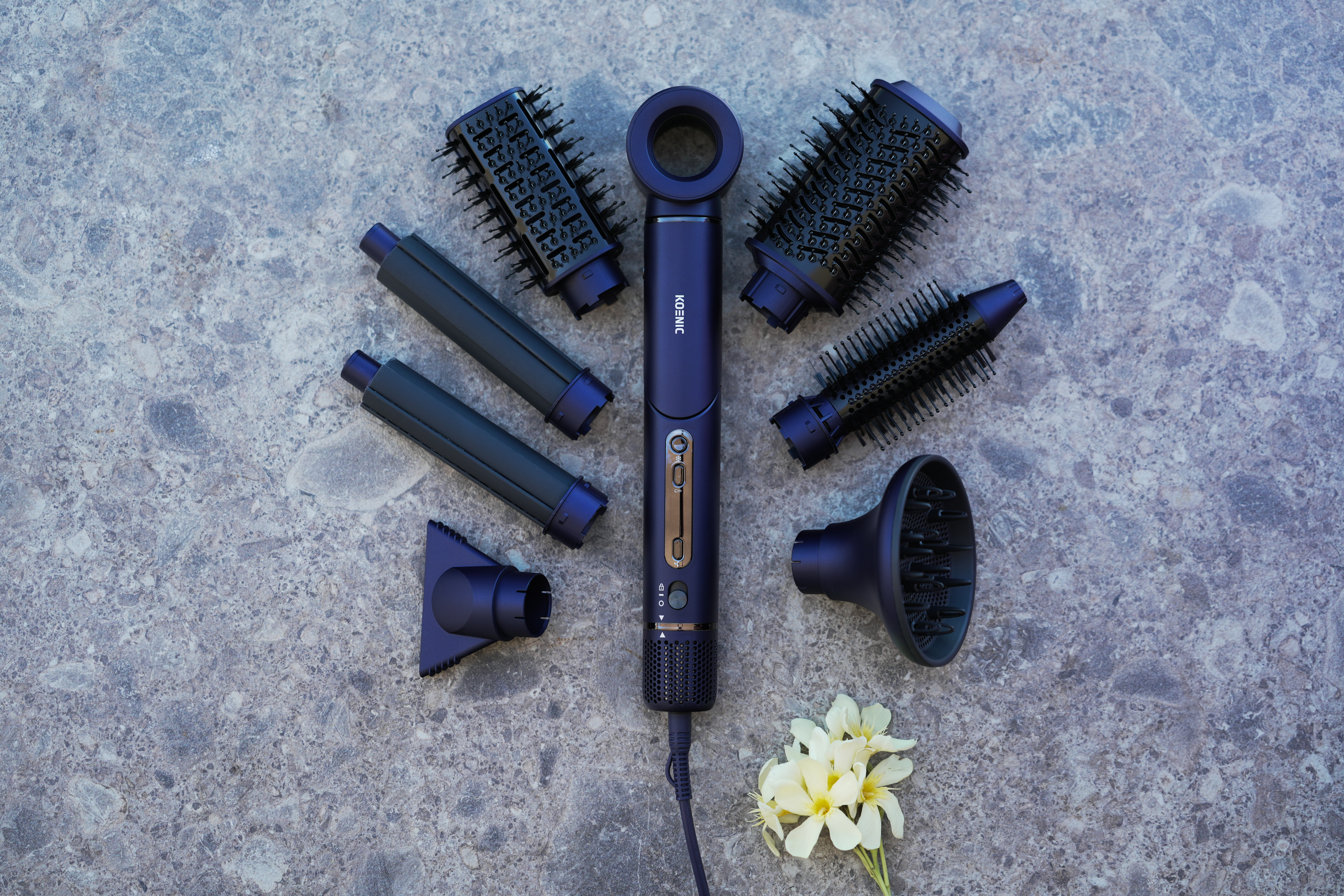 Un sèche-cheveux violet avec accessoires, y compris des brosses, des embouts et un diffuseur.