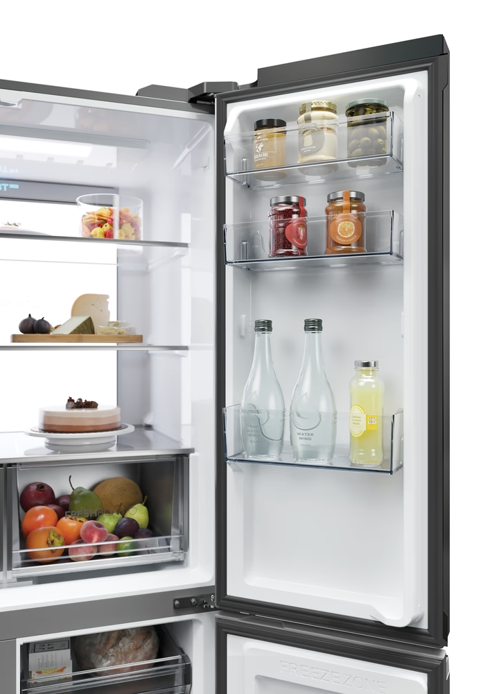 Offener Kühlschrank mit Obst, Kuchen, Käse, Gläsern und Flaschen.