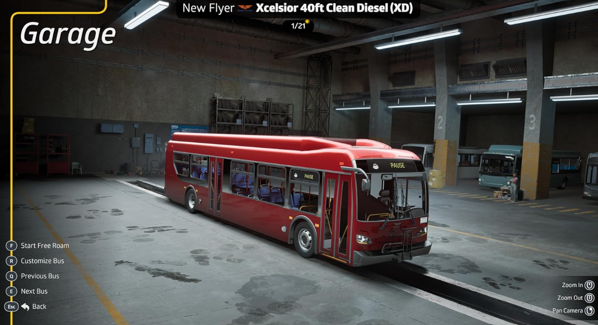 Ein roter Bus steht in einer Werkstatt mit anderen Bussen im Hintergrund.