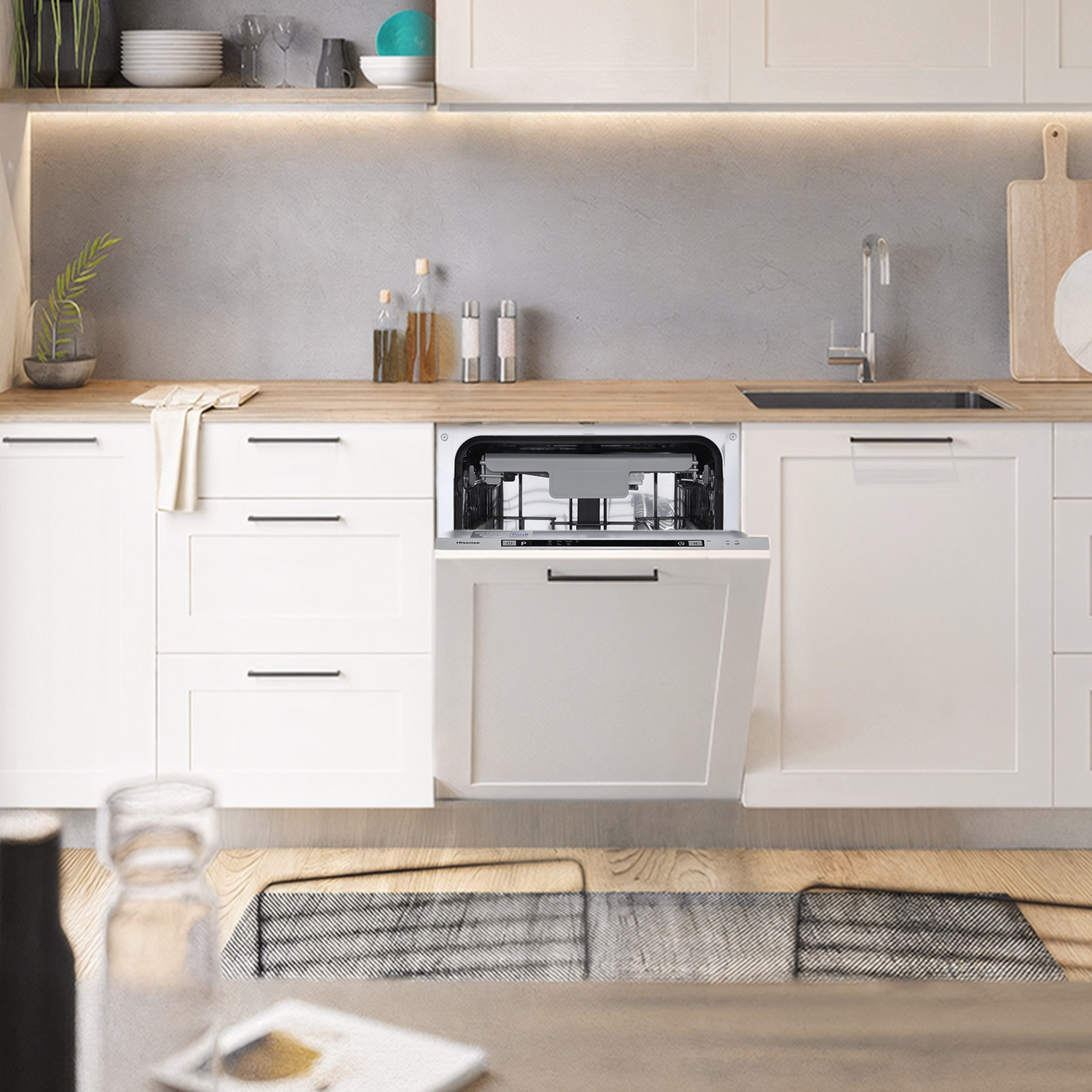 Cucina moderna con mobili bianchi, lavastoviglie aperta, lavello e piano di lavoro legno.