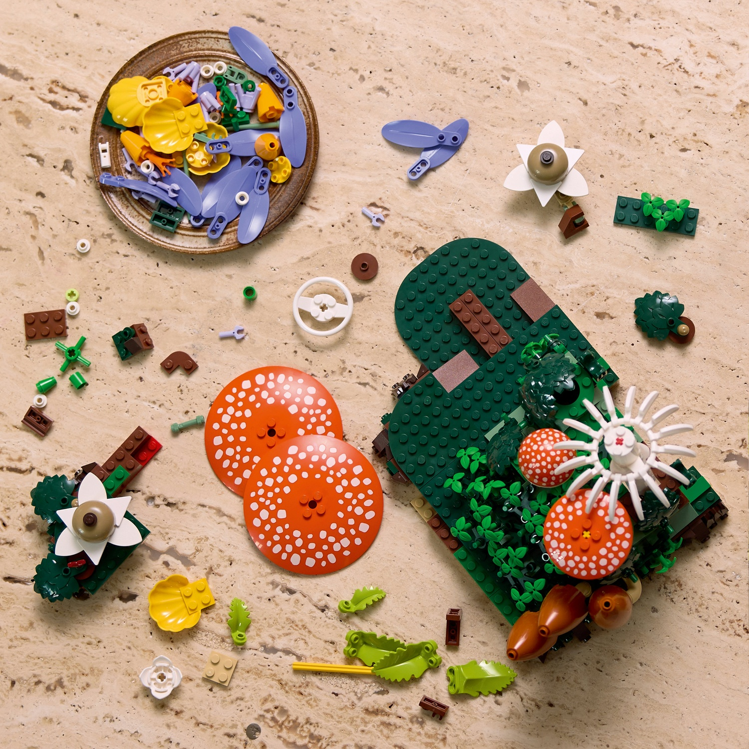 Pezzi da costruzione Lego per una scena naturale, inclusi funghi, fiori e un ragno.