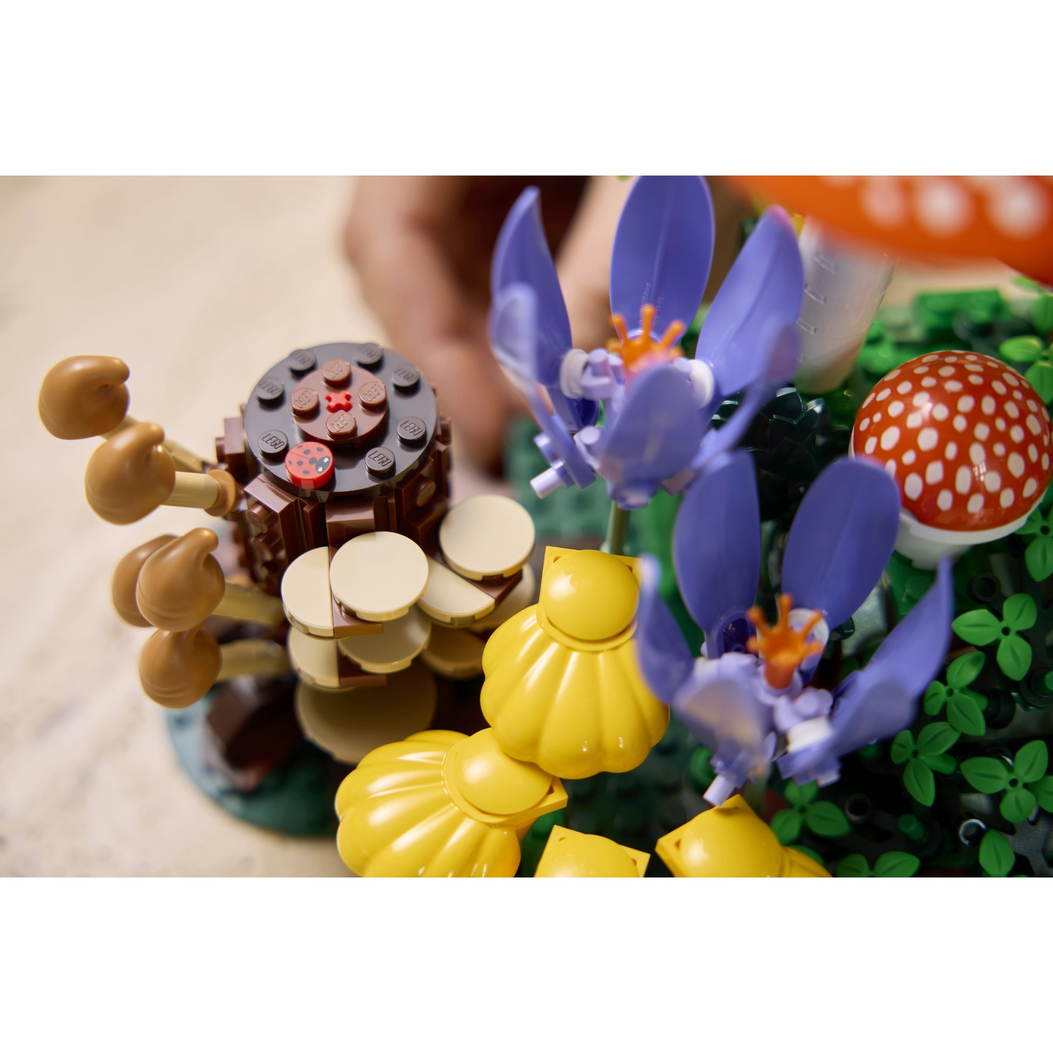 Replica Lego di un giardino con funghi, fiori e una coccinella.