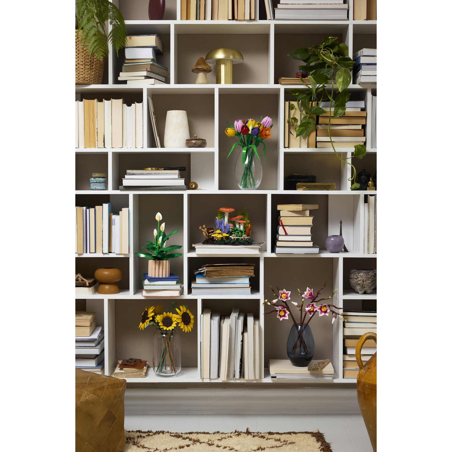 Una libreria bianca piena di libri, piante e oggetti decorativi.