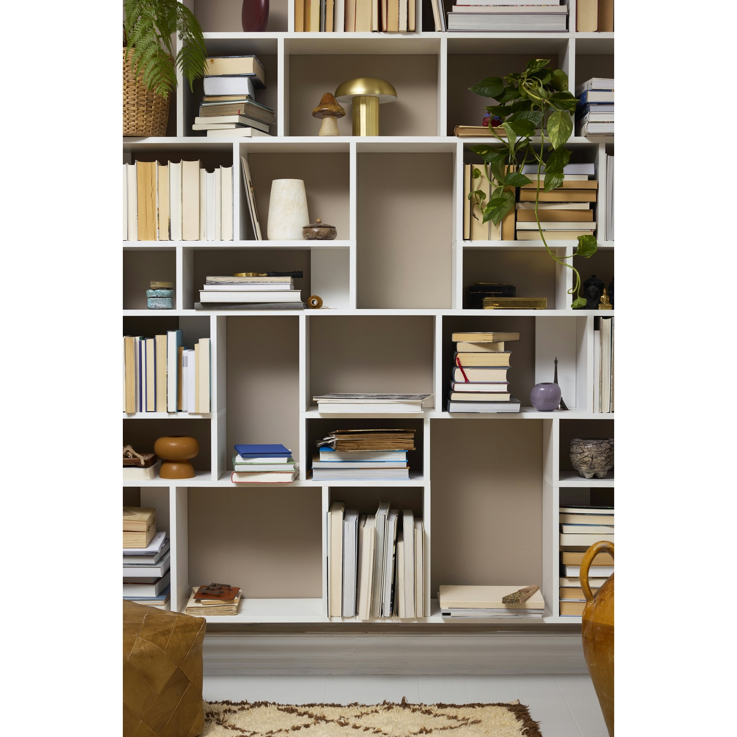 Una libreria bianca piena di libri, piante e oggetti decorativi.