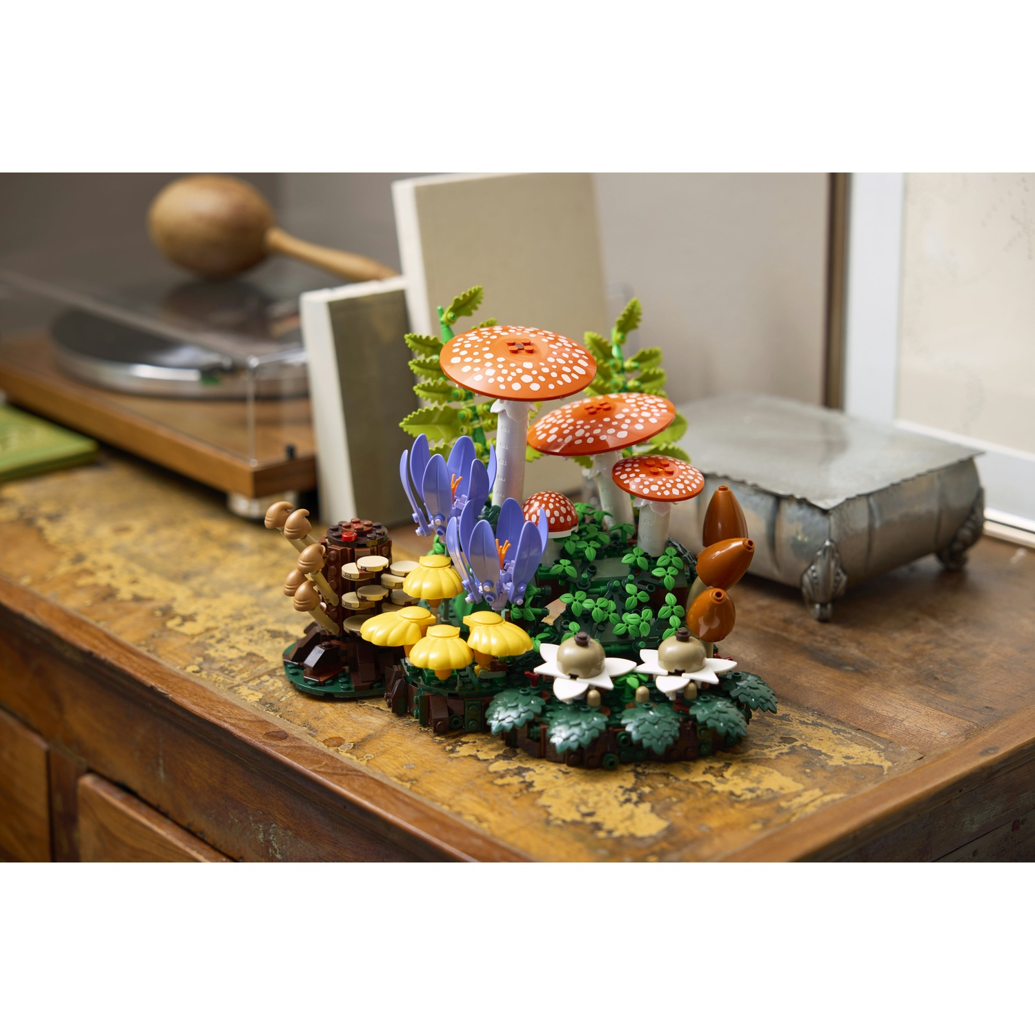 Modello Lego di funghi e piante su un tavolo di legno, con un giradischi sullo sfondo.