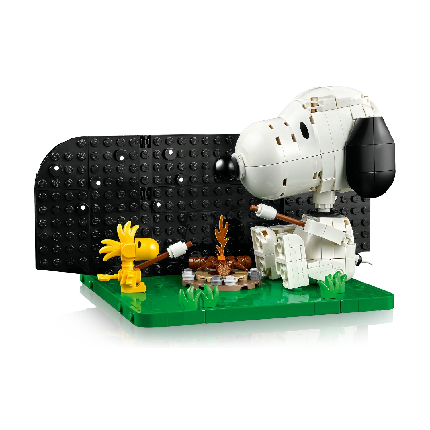 Figure Lego di Snoopy e Woodstock vicino a un falò su base verde con sfondo nero.