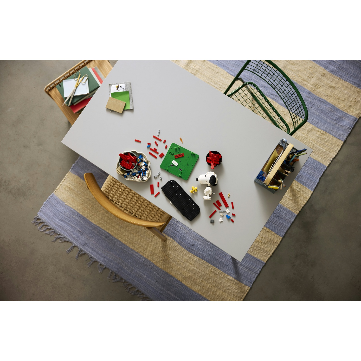 Tavolo grigio con mattoncini Lego, giocattoli e libri.