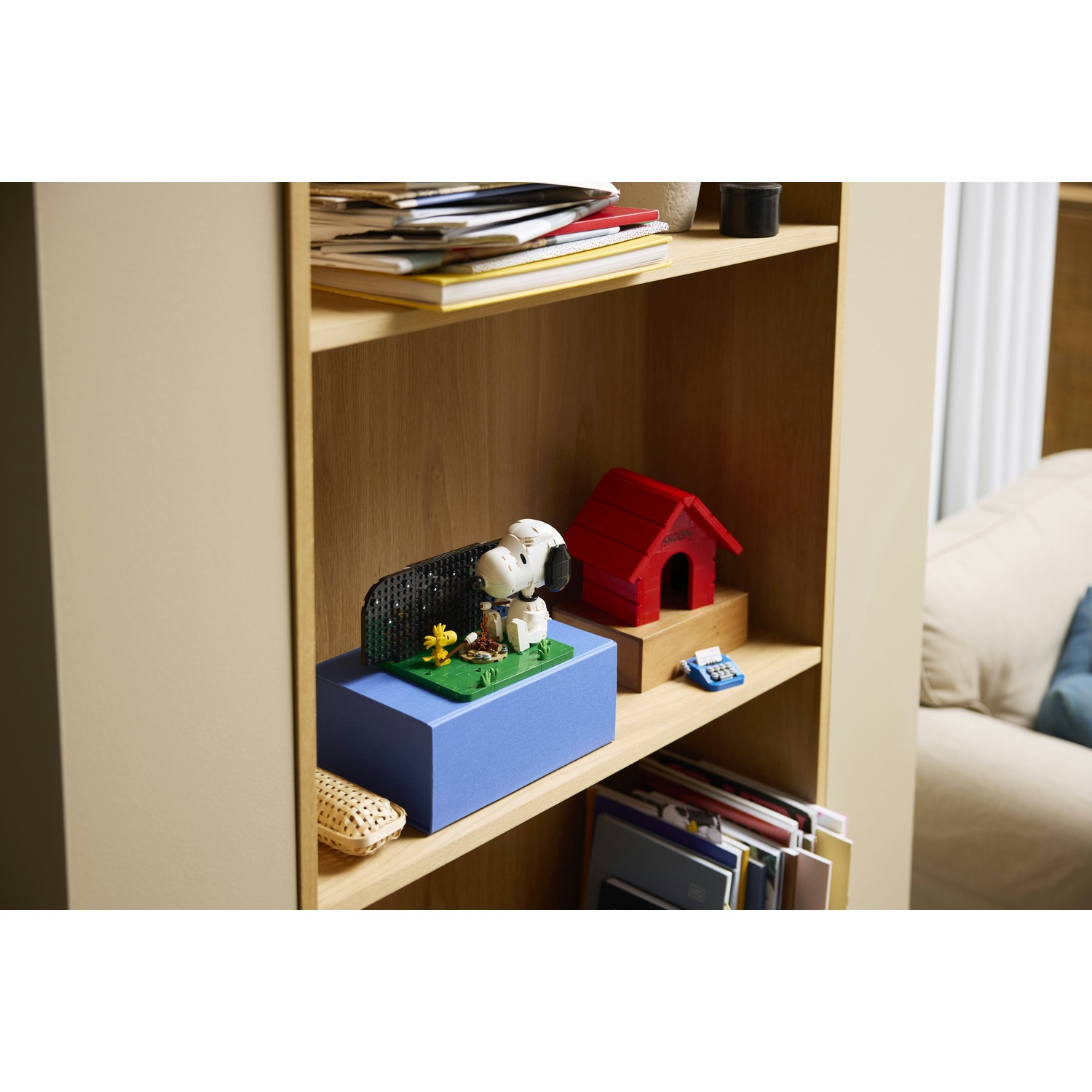 Statua di Snoopy su base blu con Woodstock vicino a cuccia rossa.