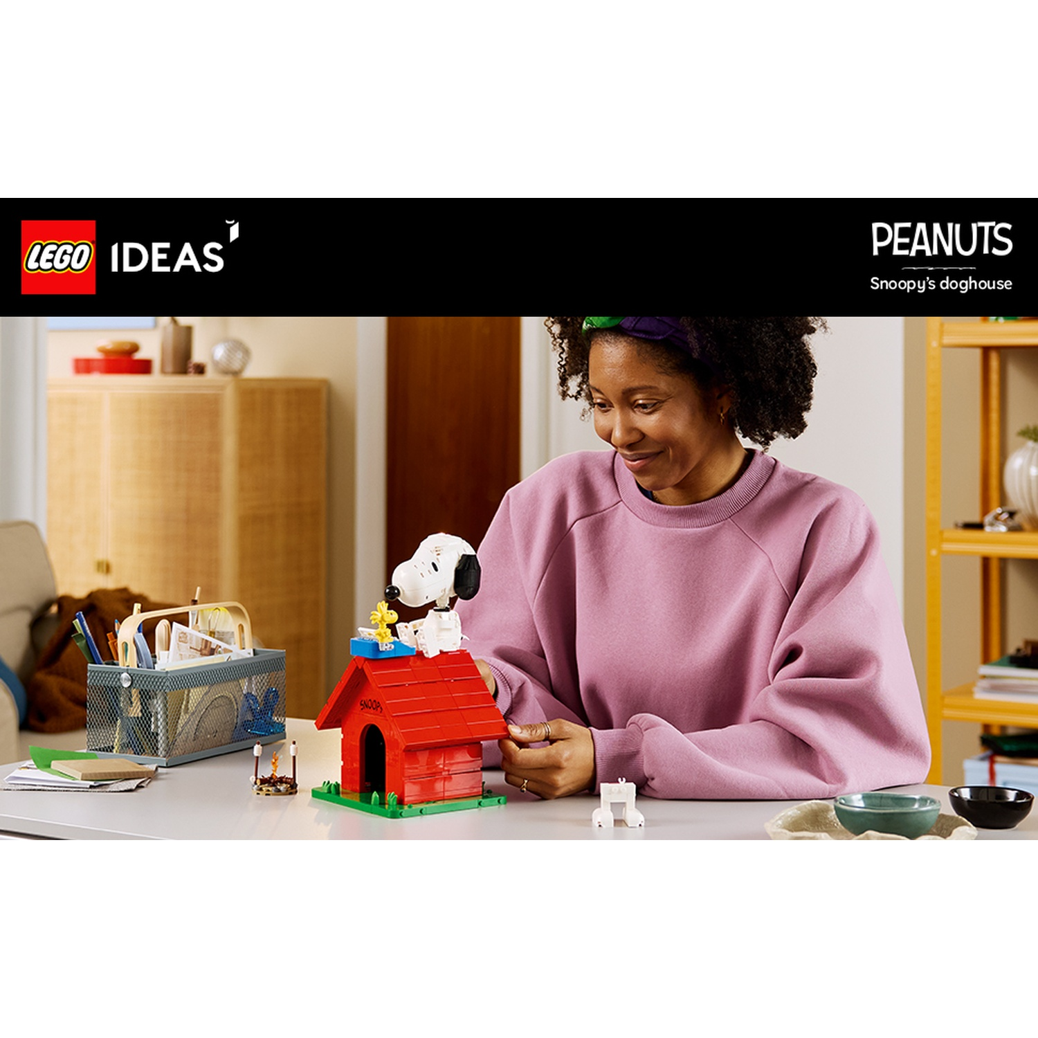 Donna costruisce la cuccia di Snoopy con Lego. Snoopy e Woodstock sono sopra.