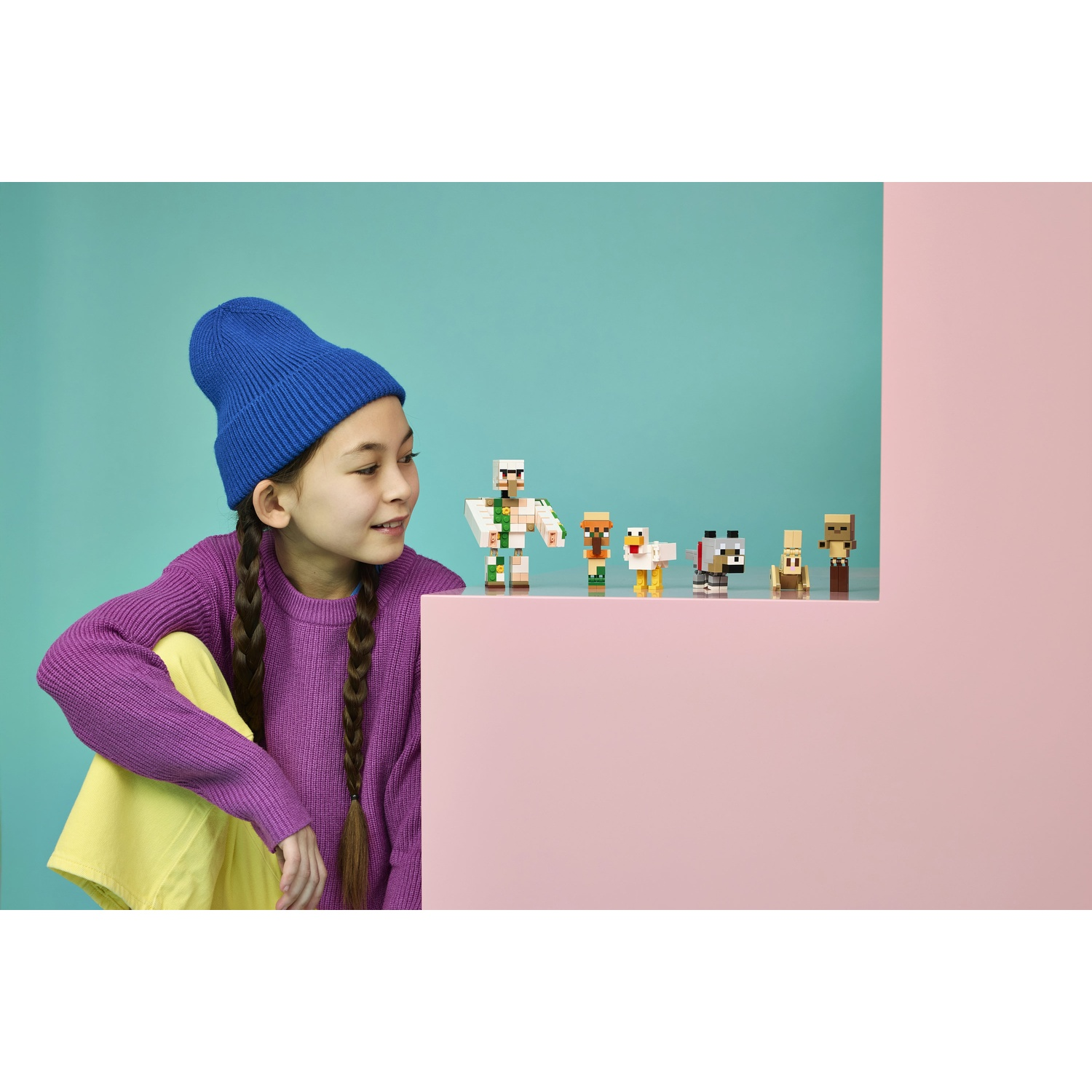 Bambina con cappello blu e maglione viola guarda figure Minecraft.