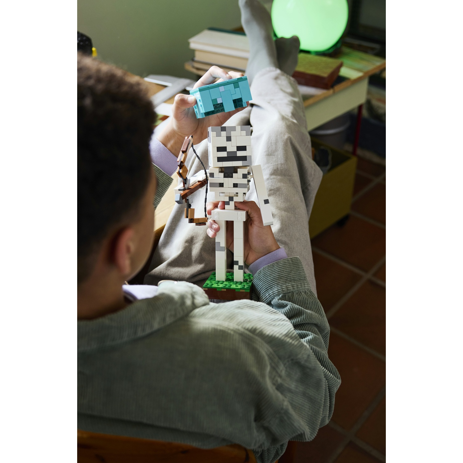Persona tiene figura scheletro Minecraft e blocco blu.