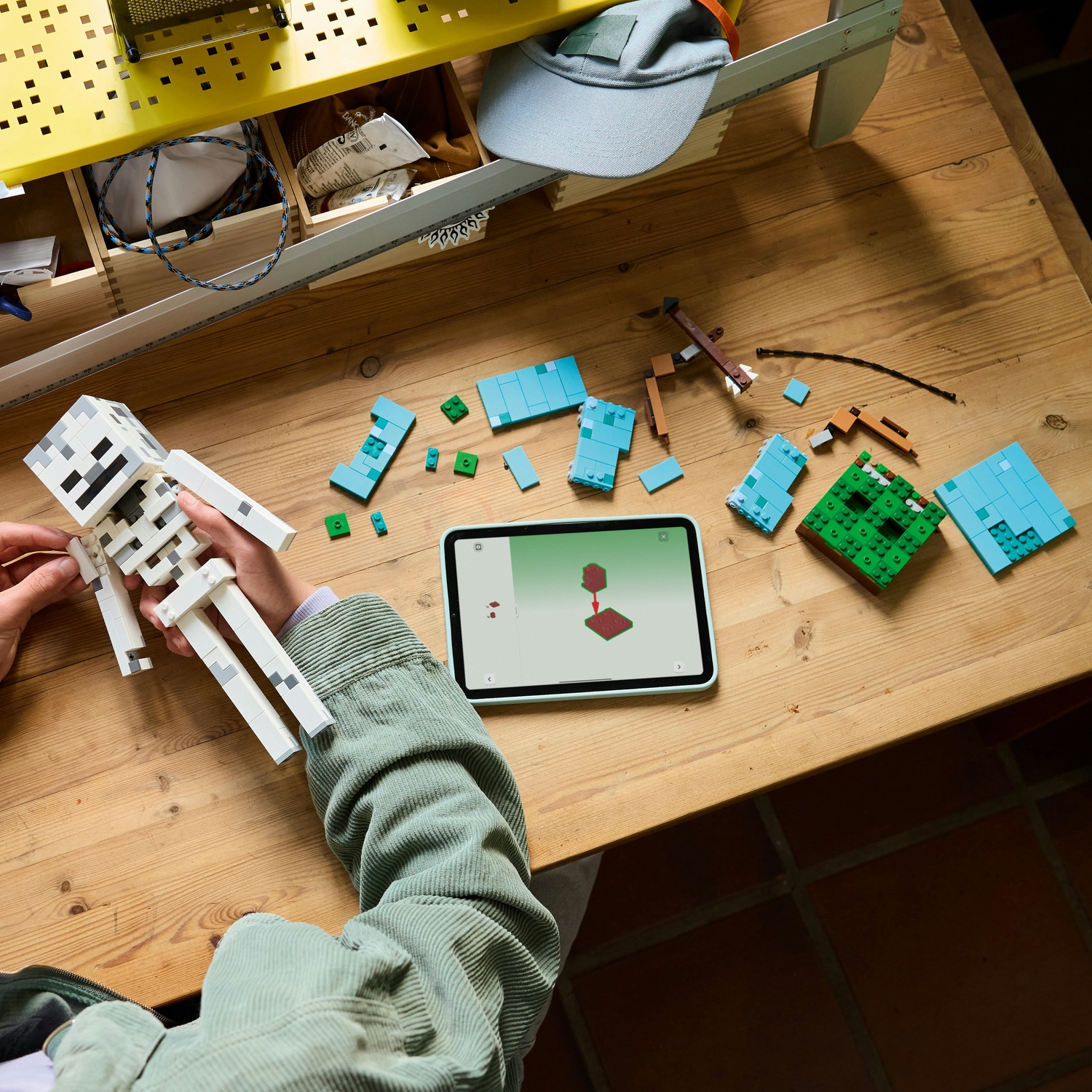 Bambino costruisce scheletro con mattoncini Lego, istruzioni su tablet, tavolo legno