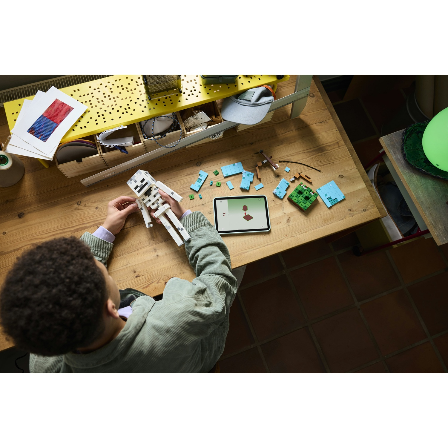 Un bambino costruisce uno scheletro con mattoncini LEGO su un tavolo di legno.