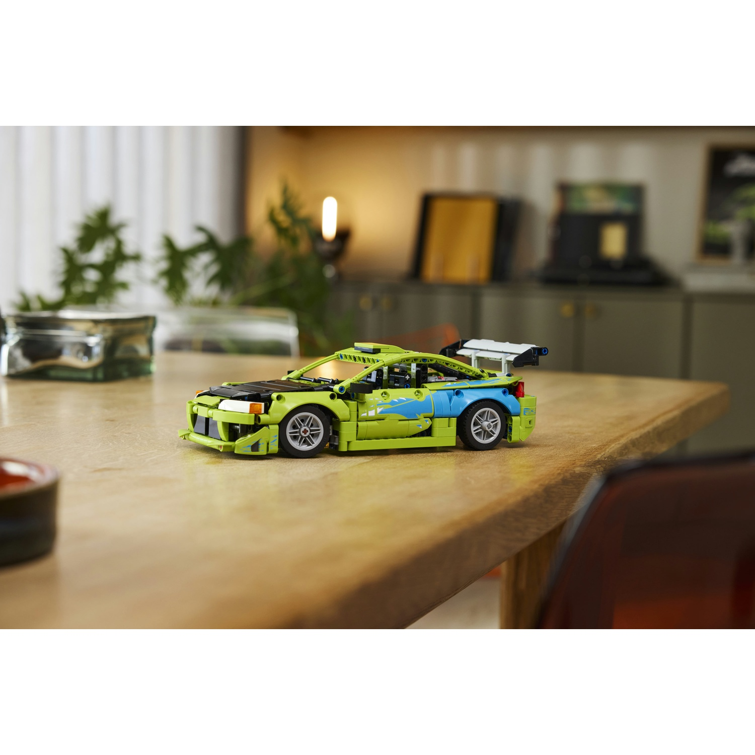 Un'auto Lego verde e blu con spoiler si trova su un tavolo di legno.
