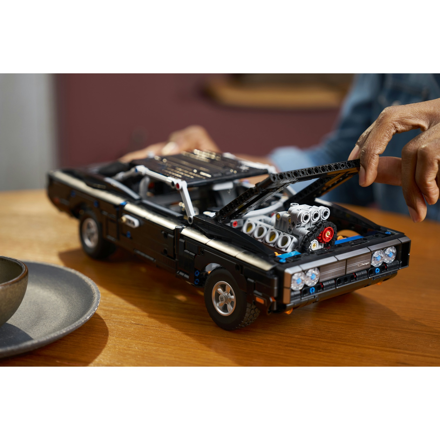Un'auto Lego nera con il cofano aperto che rivela il motore.