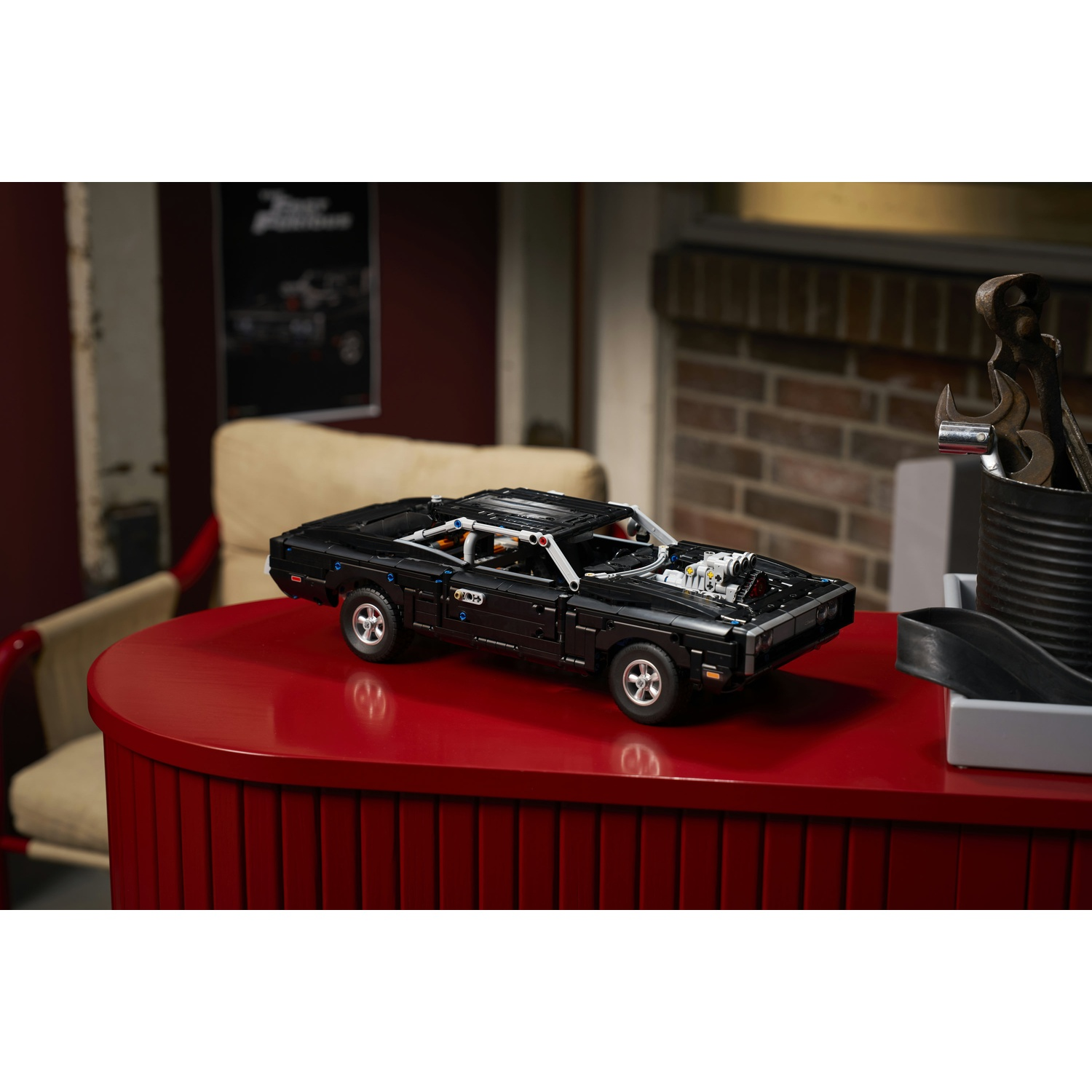Modello Lego nero di una Dodge Charger con cofano aperto, su un tavolo rosso.