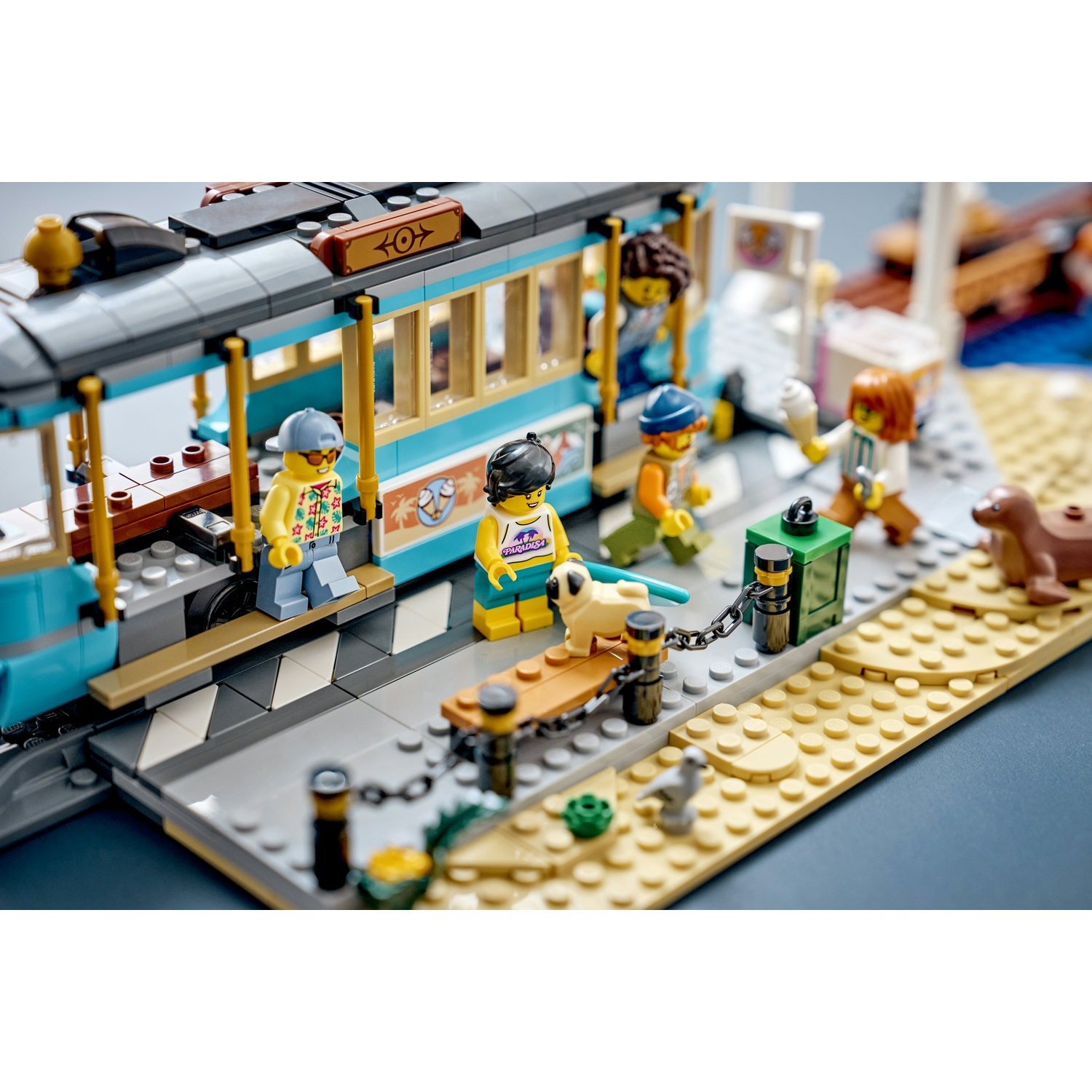 Scena spiaggia Lego con tram, figure, cane e foca sulla sabbia.