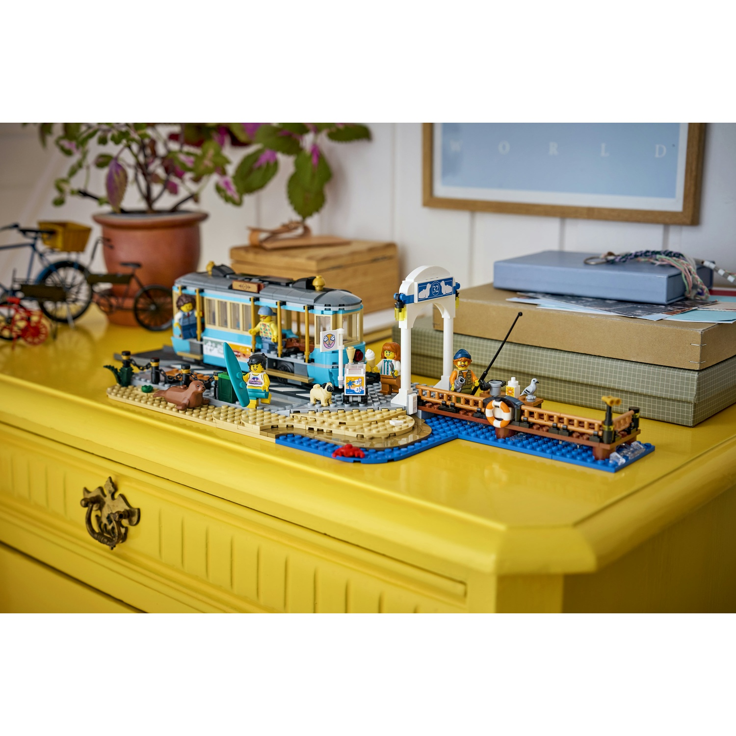 Modello di tram Lego sulla spiaggia con figure e un molo con un pescatore.