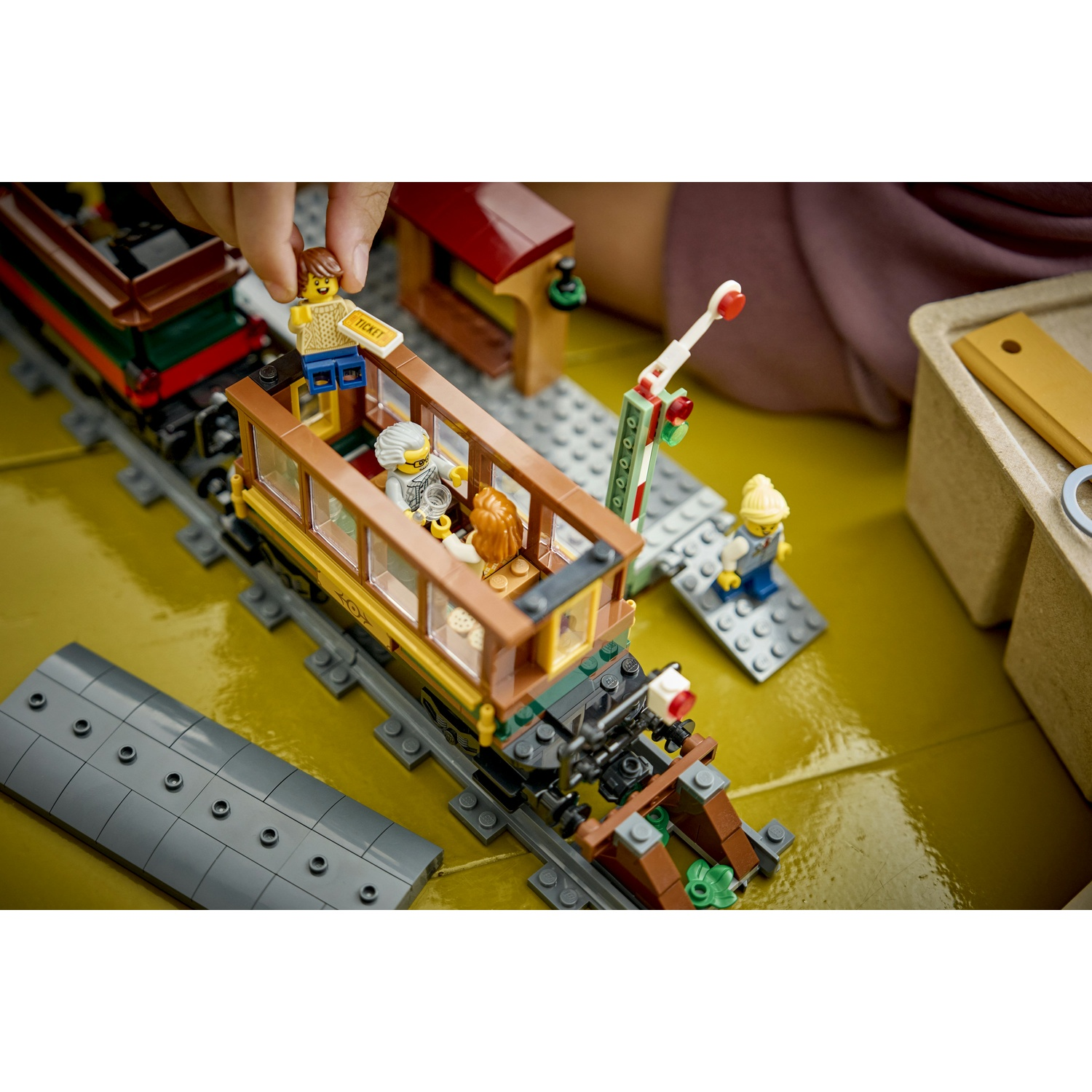 Treno LEGO con figure e un segnale di passaggio a livello sui binari.