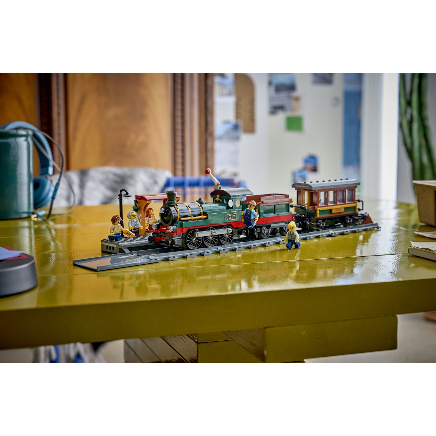 Un modello di treno Lego con figure e carrozze su un tavolo giallo.