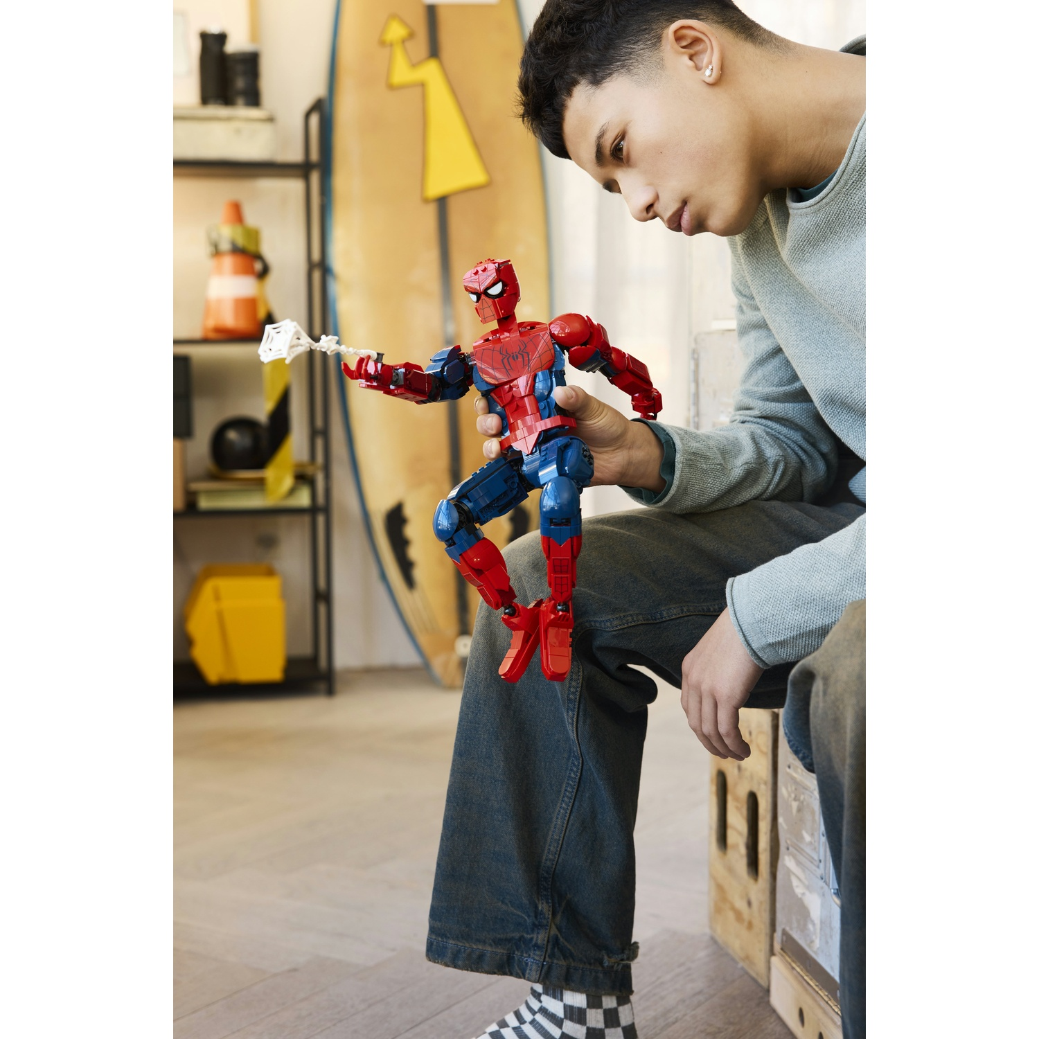 Un giovane tiene in mano un action figure di Spider-Man rosso e blu con una ragnatela bianca.