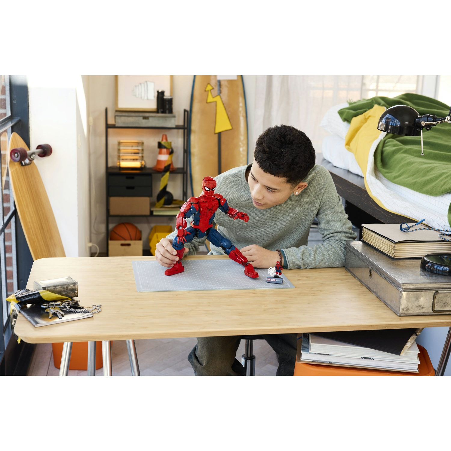 Un ragazzo seduto a una scrivania gioca con un action figure di Spider-Man.