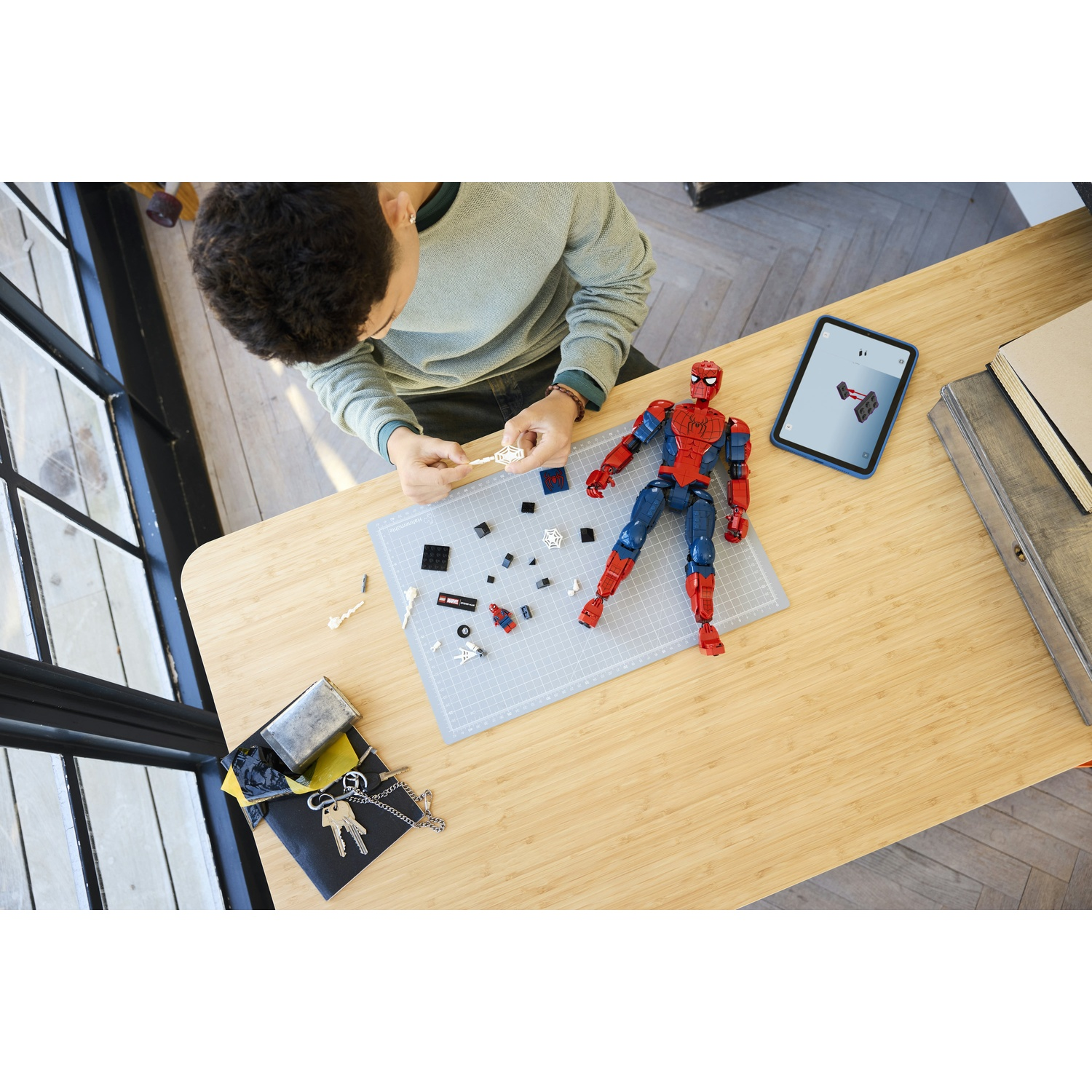Un ragazzo costruisce una figura di Spiderman su un tavolo con pezzi.