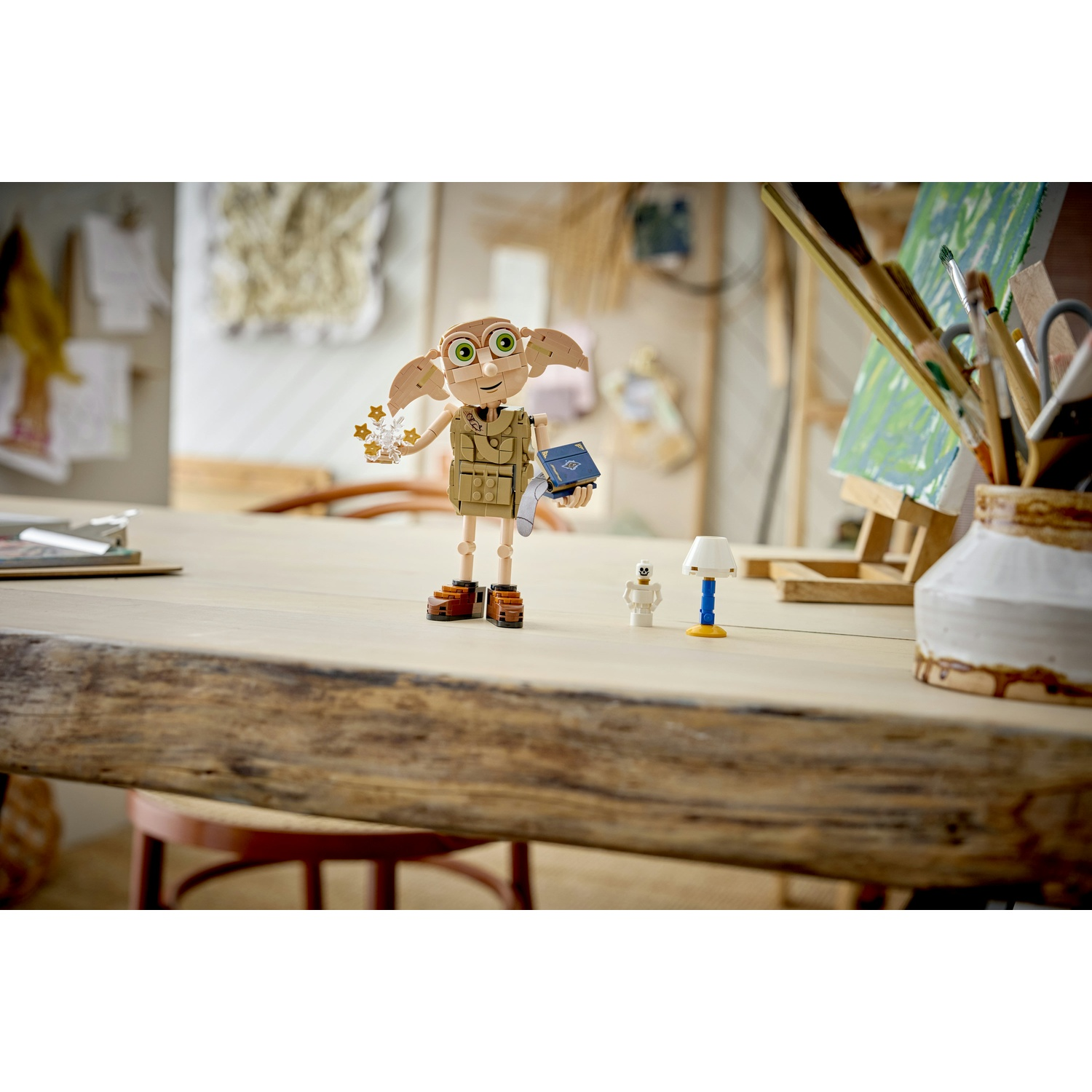 Personaggio LEGO Dobby tiene stelle, accanto a libro, lampada e scheletro.