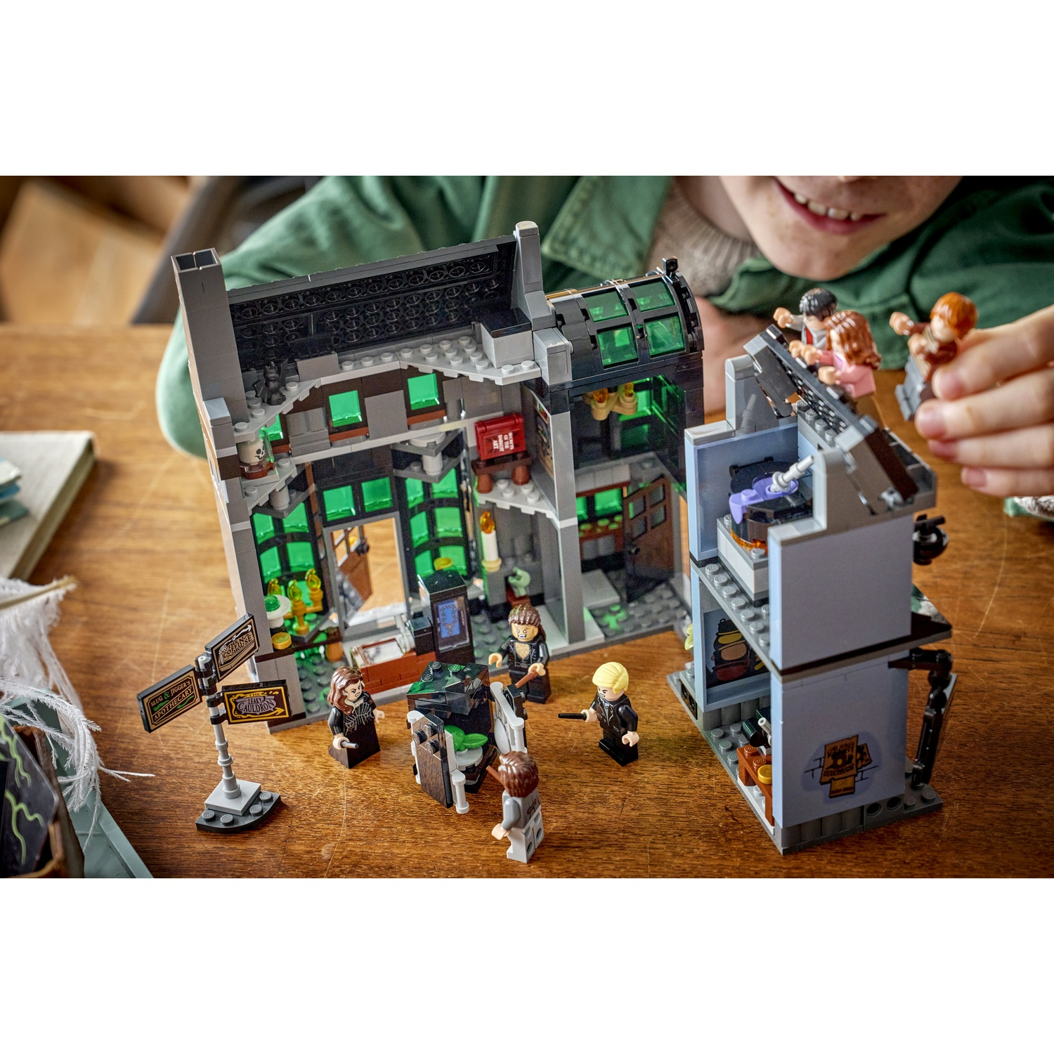 Un bambino gioca con un modello Lego che raffigura un edificio con figure.
