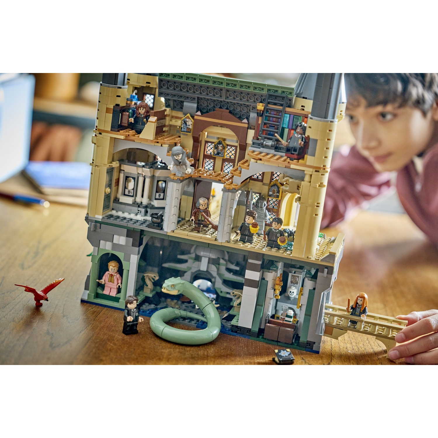 Un bambino gioca con un set Lego di Hogwarts con un serpente e minifigure.