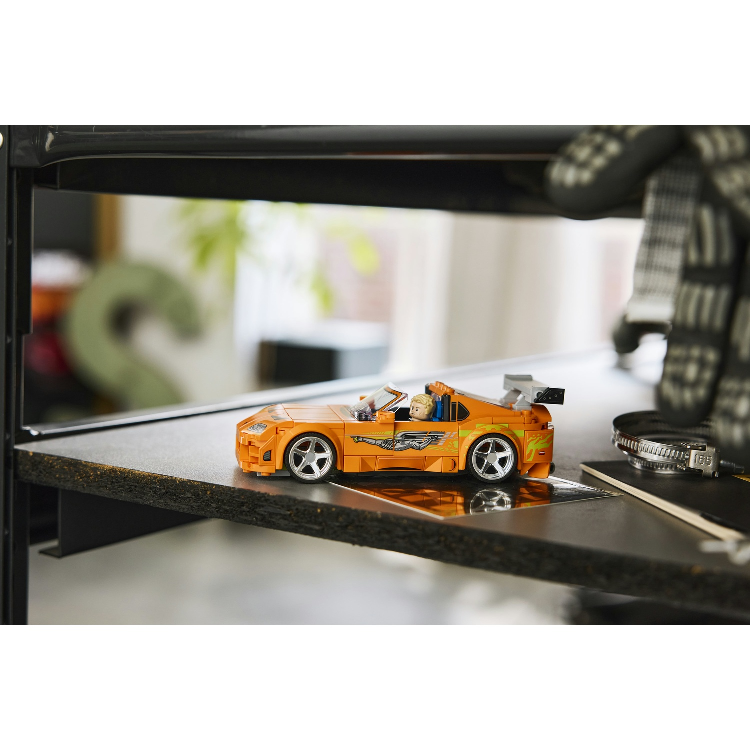 Auto sportiva LEGO arancione con minifigure su uno scaffale.