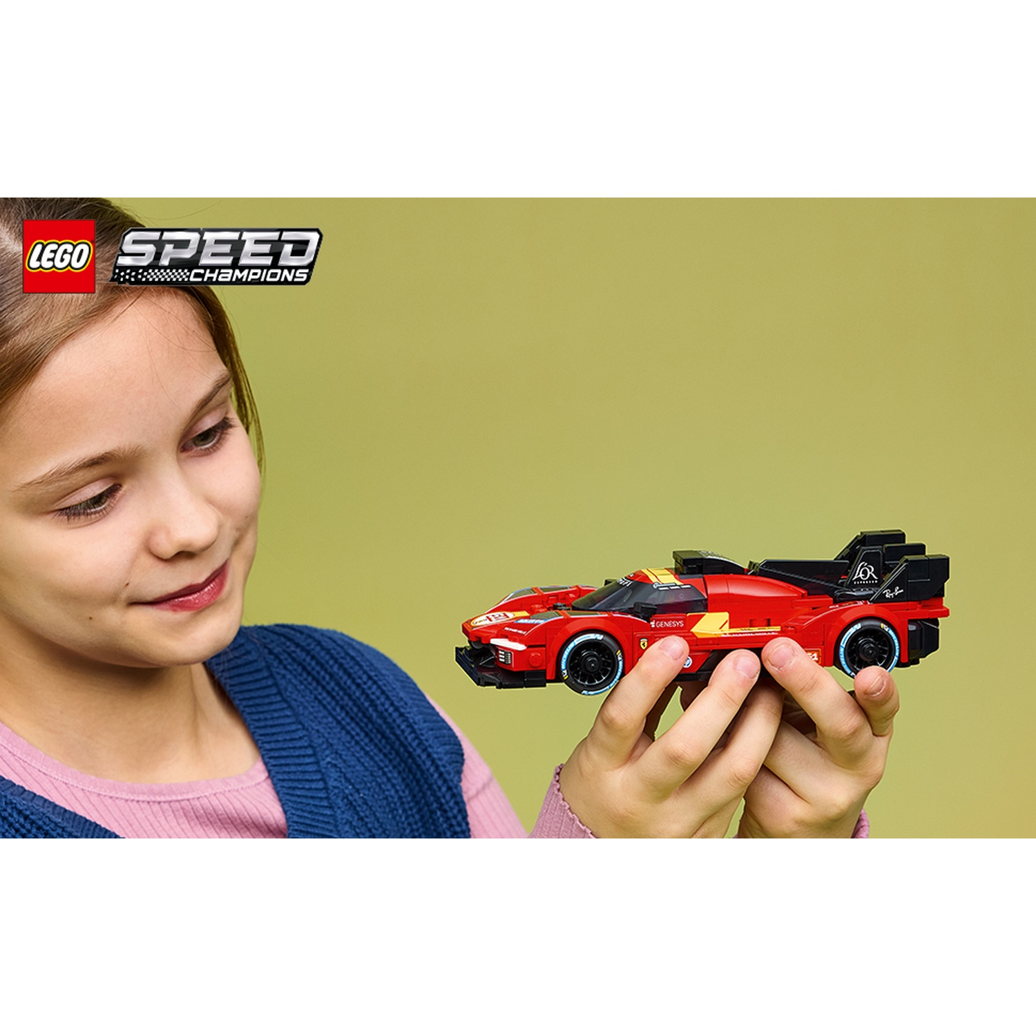 Una bambina tiene un'auto da corsa Lego rossa con strisce gialle e il logo 'GENESYS'.