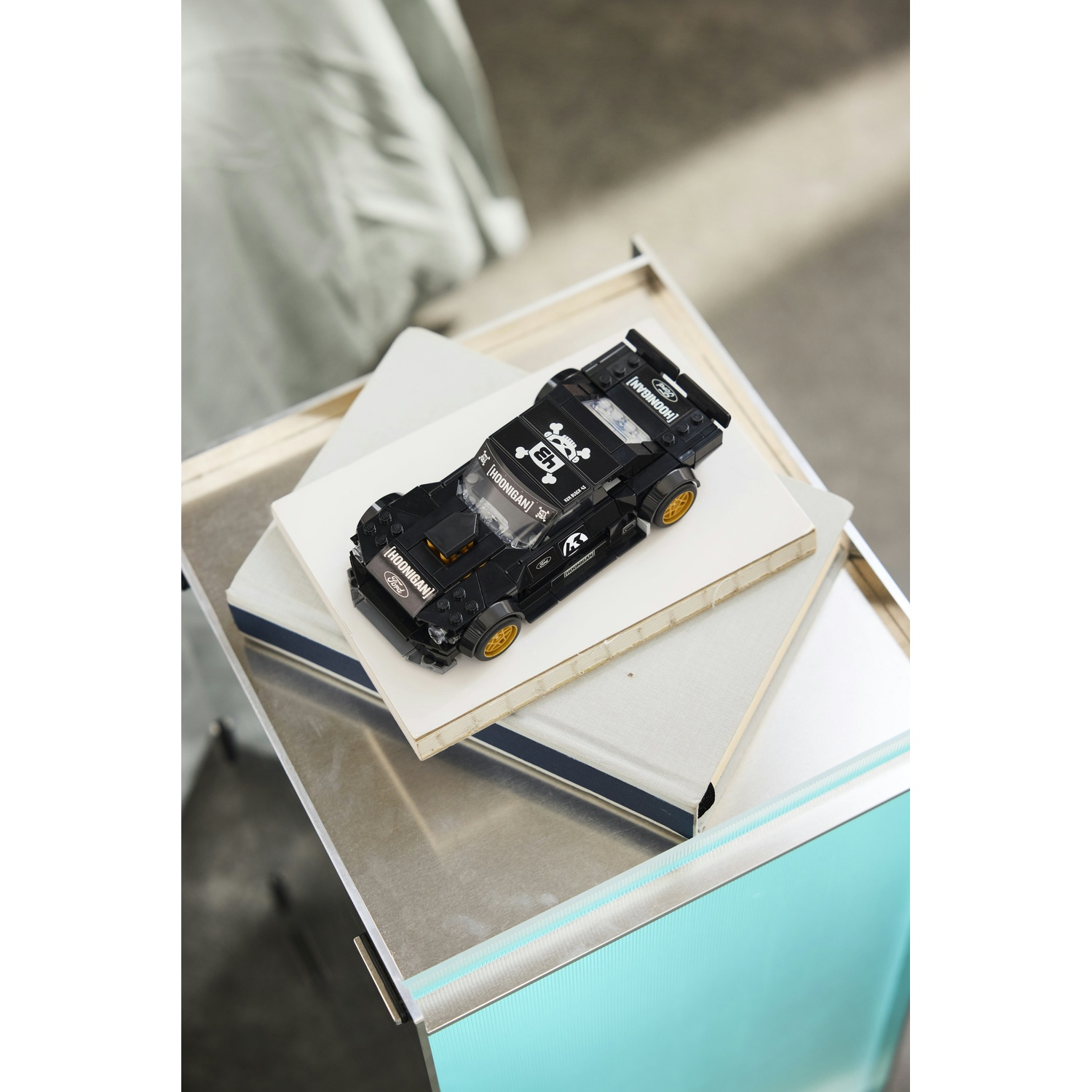 Una Ford Mustang Hoonicorn Lego nera siede sui libri su un vassoio di metallo.