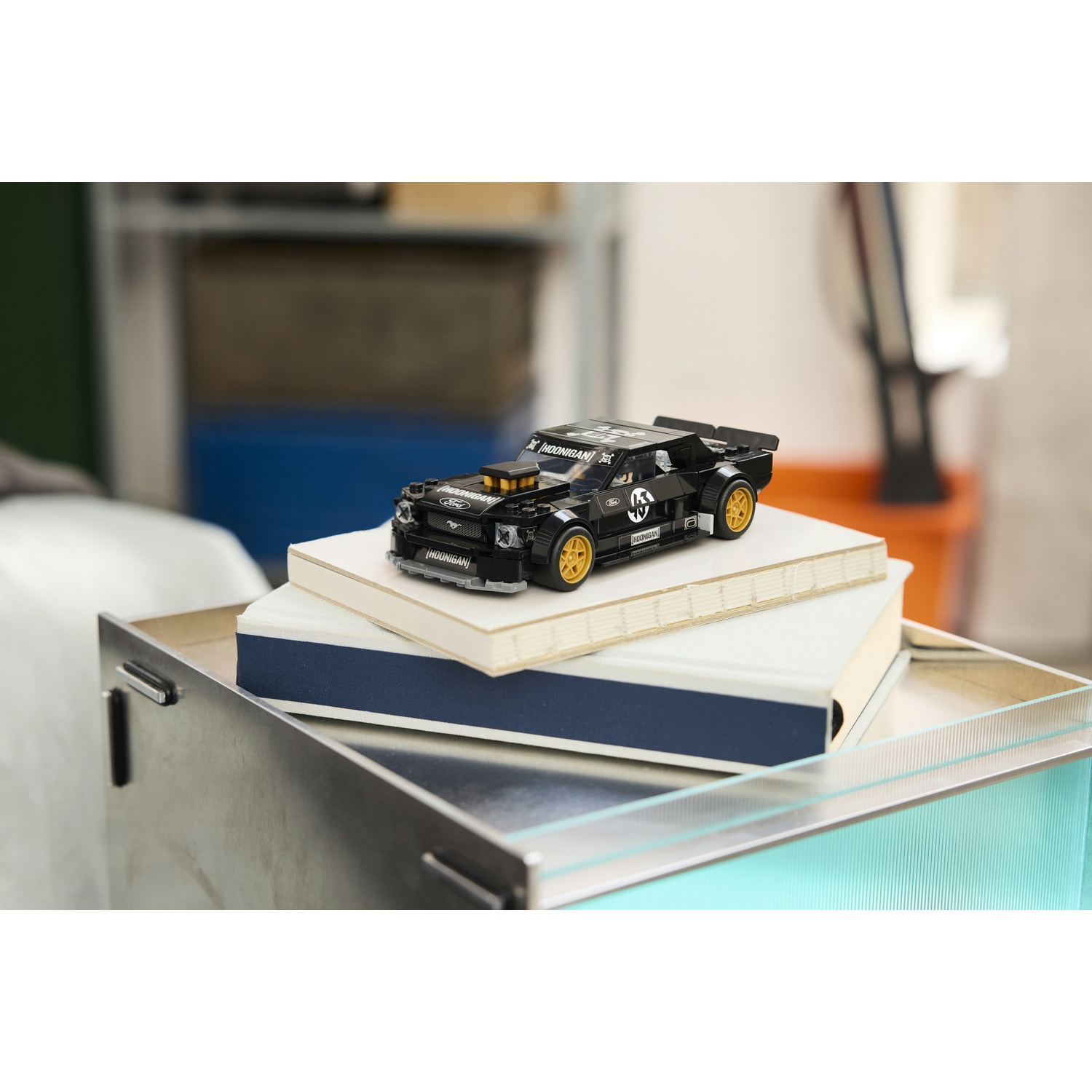 Auto Lego nera con ruote dorate su libri in un vassoio di metallo.
