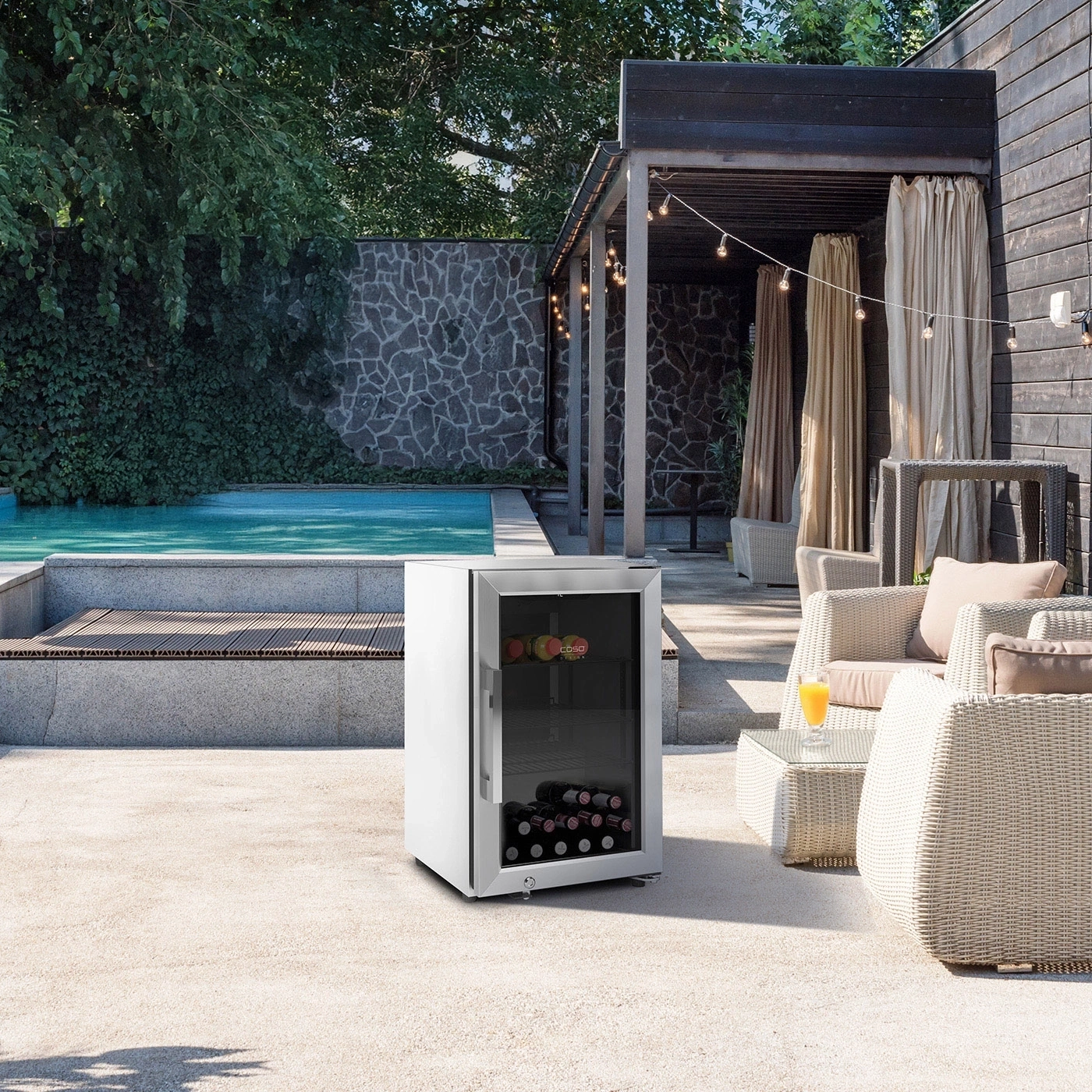 Außenterrasse mit weißem Minikühlschrank, Pool, Sitzgelegenheiten und Lichterkette.