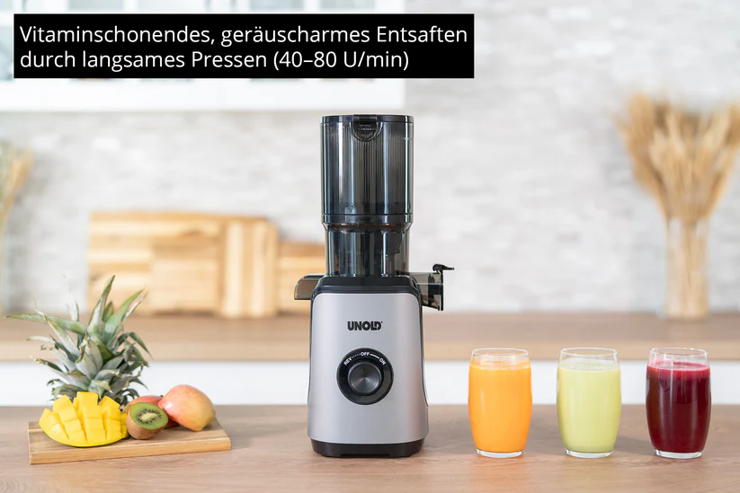 Ein silberner Entsafter steht neben drei Gläsern Saft und Früchten.