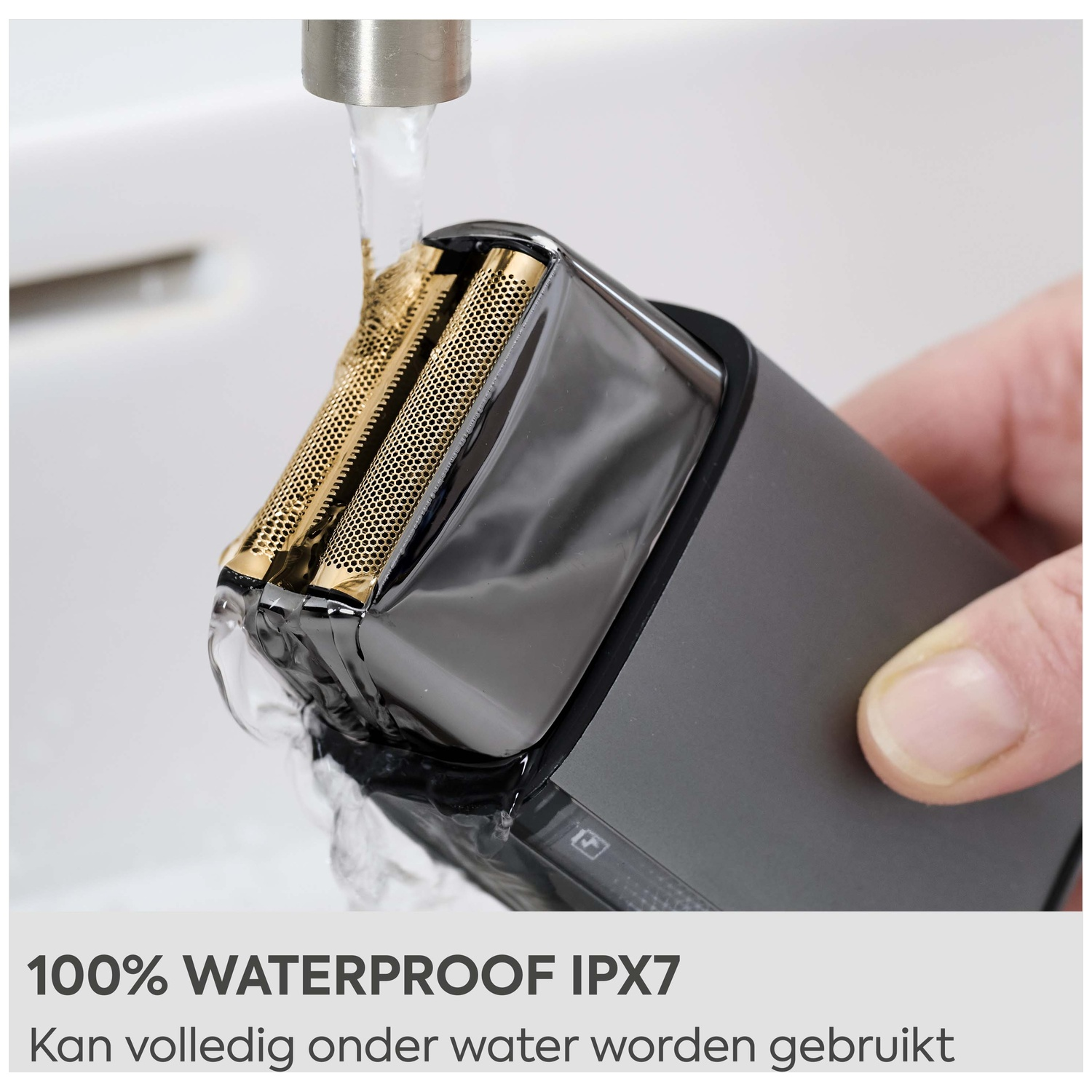 An electric shaver is being rinsed under running water.