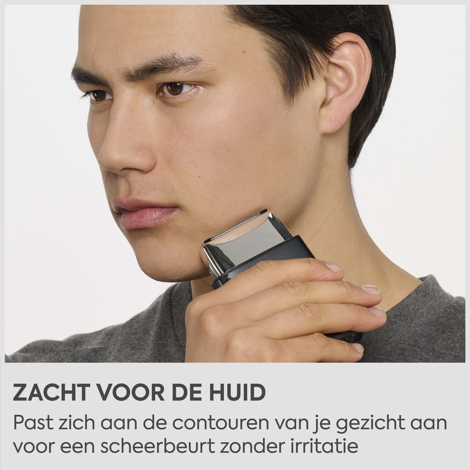 Man scheert zijn kin bij zijn oor met een zwarte elektrische scheerapparaat.