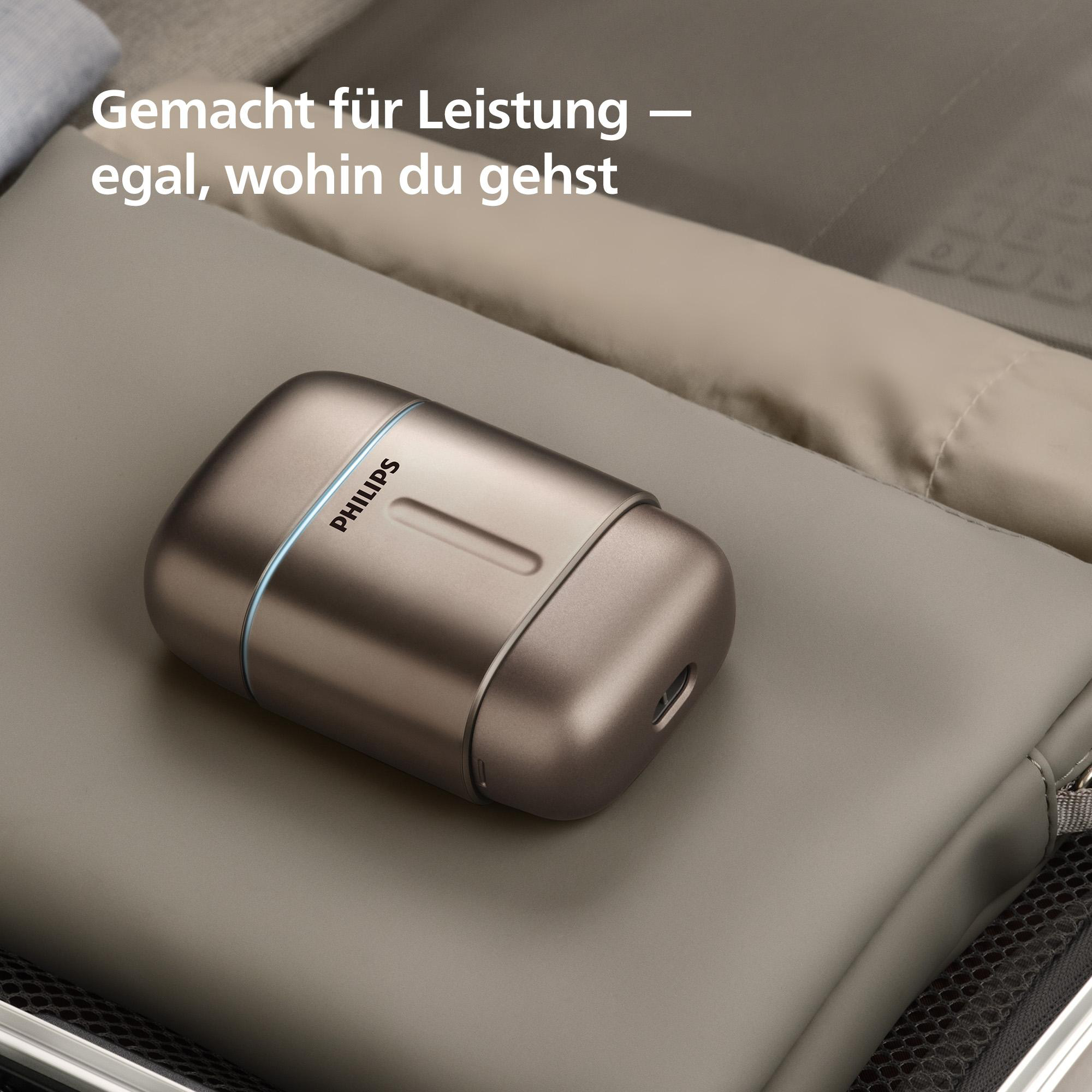 Ein bronzefarbener Philips Rasierer liegt auf einem grauen Stoff.