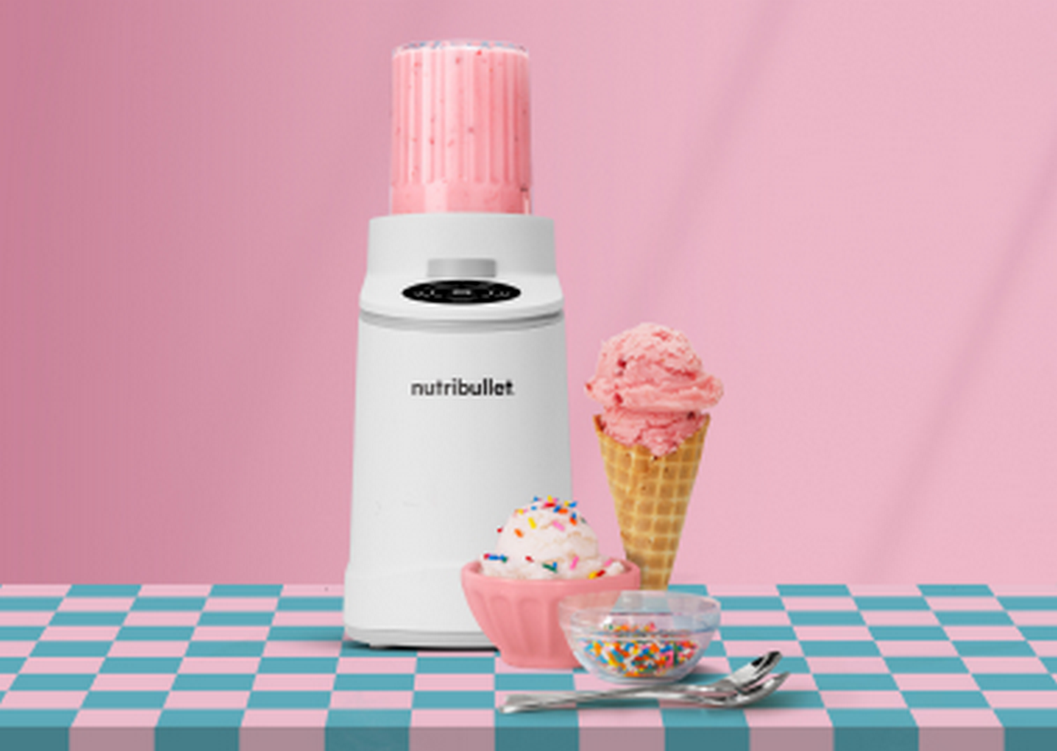 Batidora blanca con batido rosa, cono y tazón de helado, y chispas.