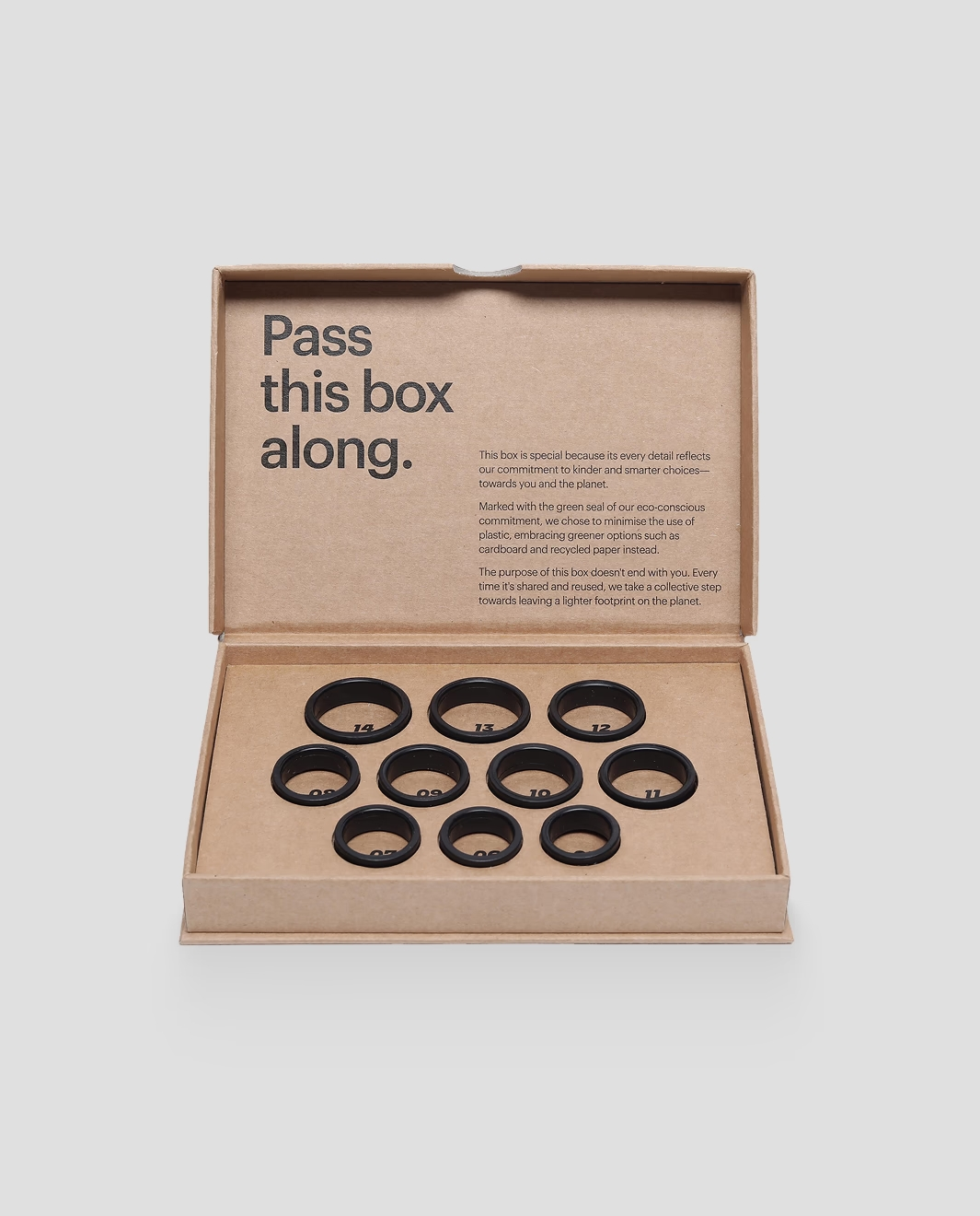 Caja de cartón abierta con 10 anillos negros numerados y dispuestos en filas.