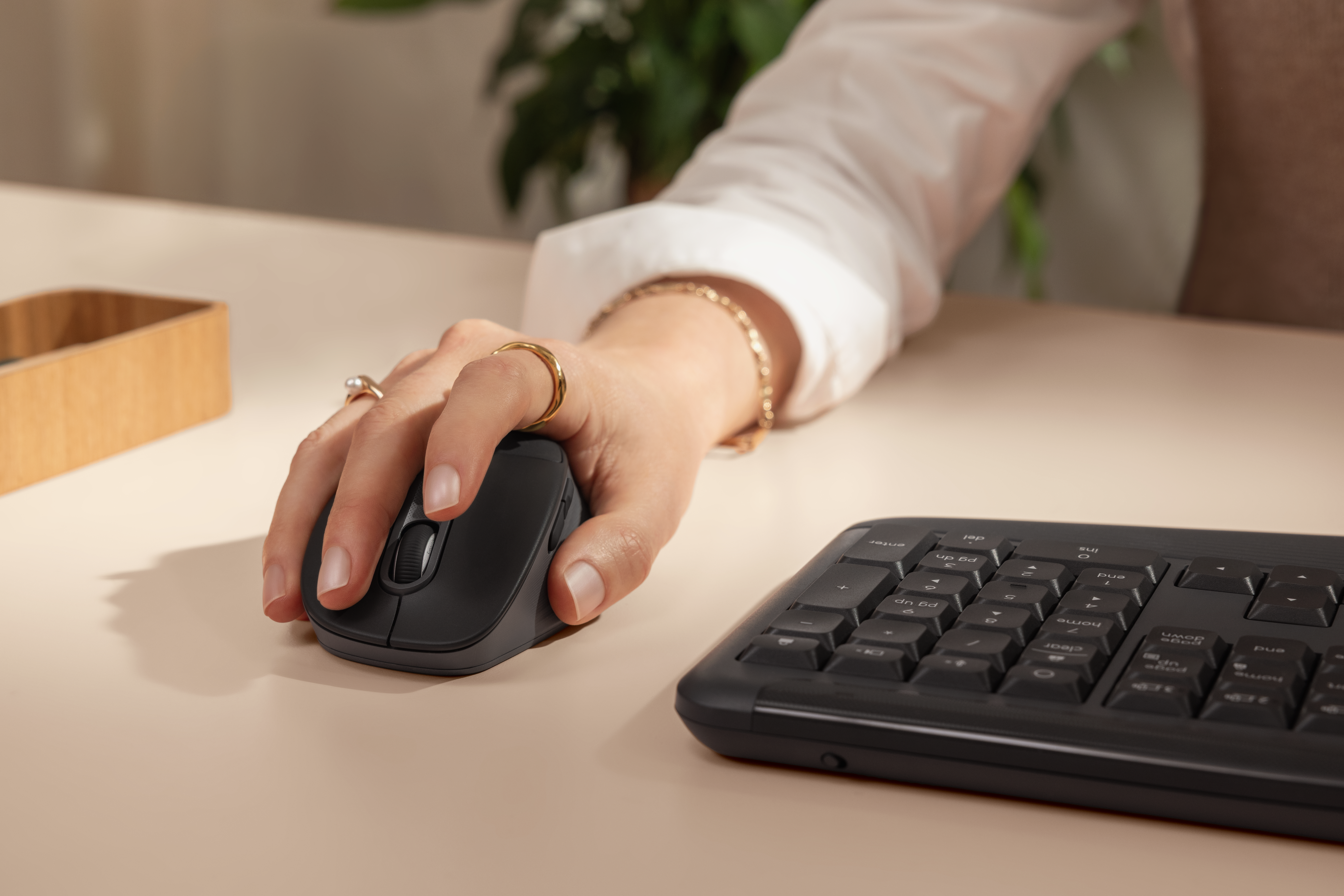 Ratón negro M850 L junto a un teclado sobre un escritorio.