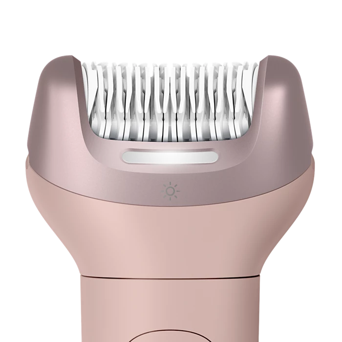 Primer plano de una depiladora oro rosa con pinzas blancas y una tira de luz.